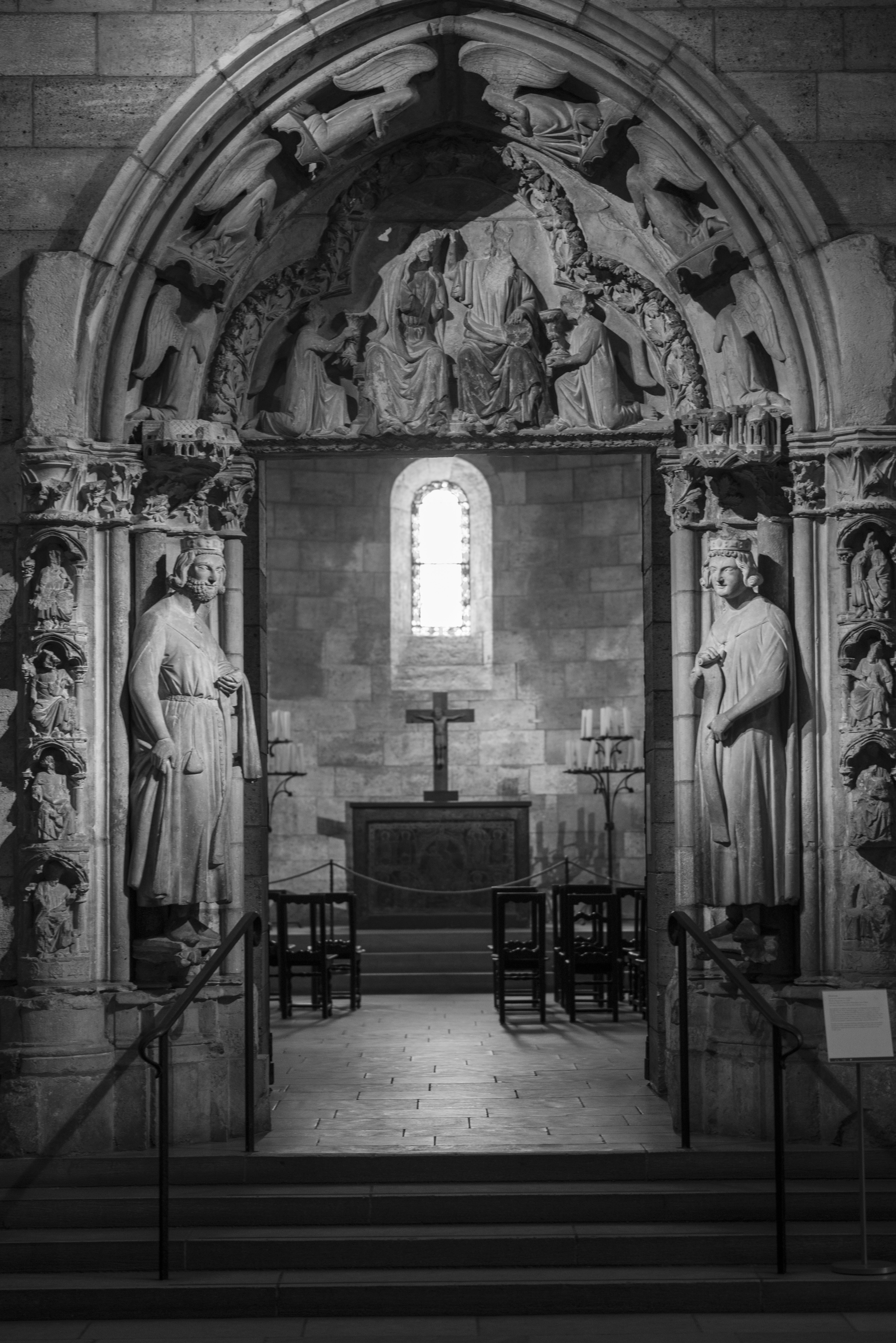 Ornate stone archway leading to a chapel with a cross