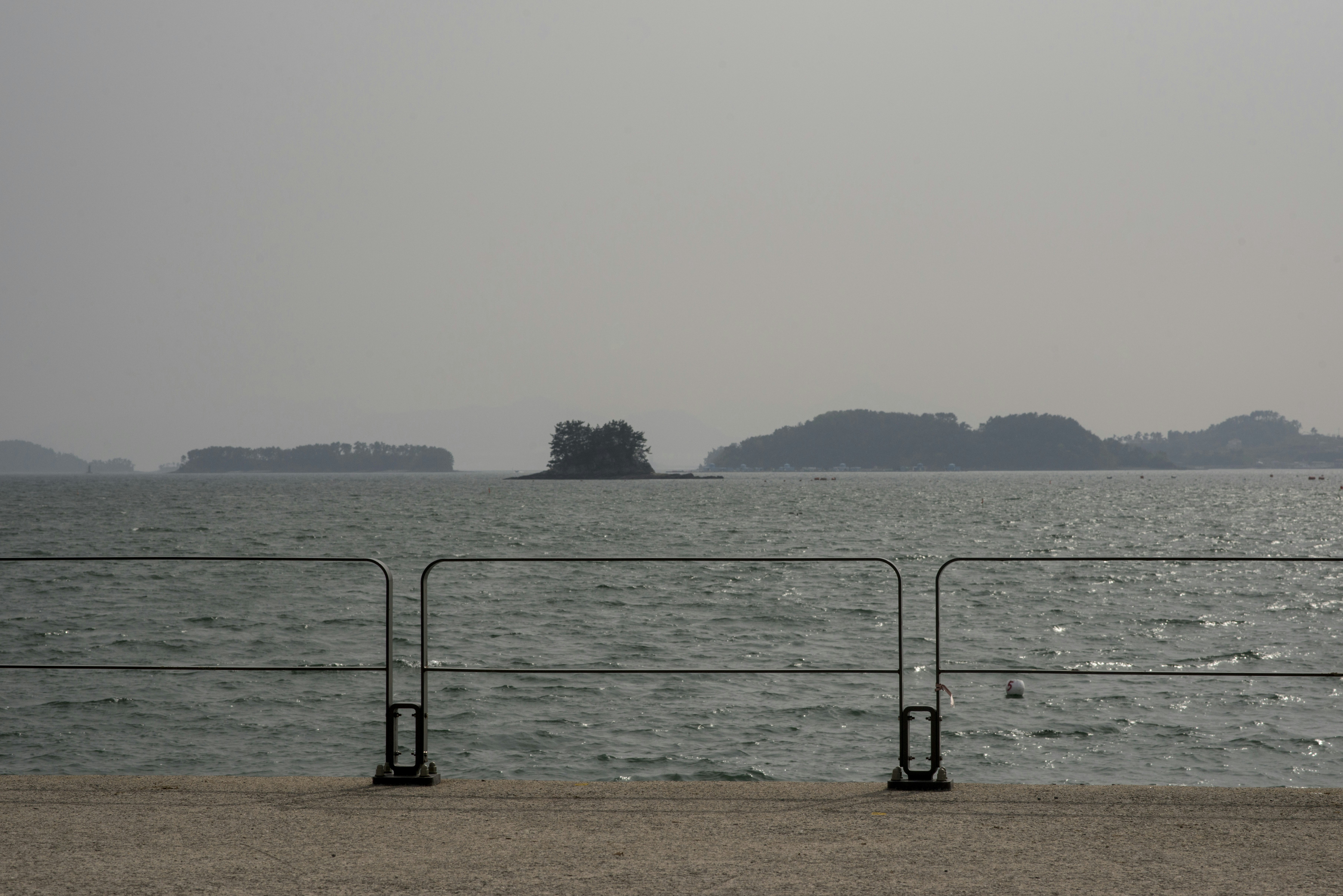 Ocean view with distant islands and a metal railing