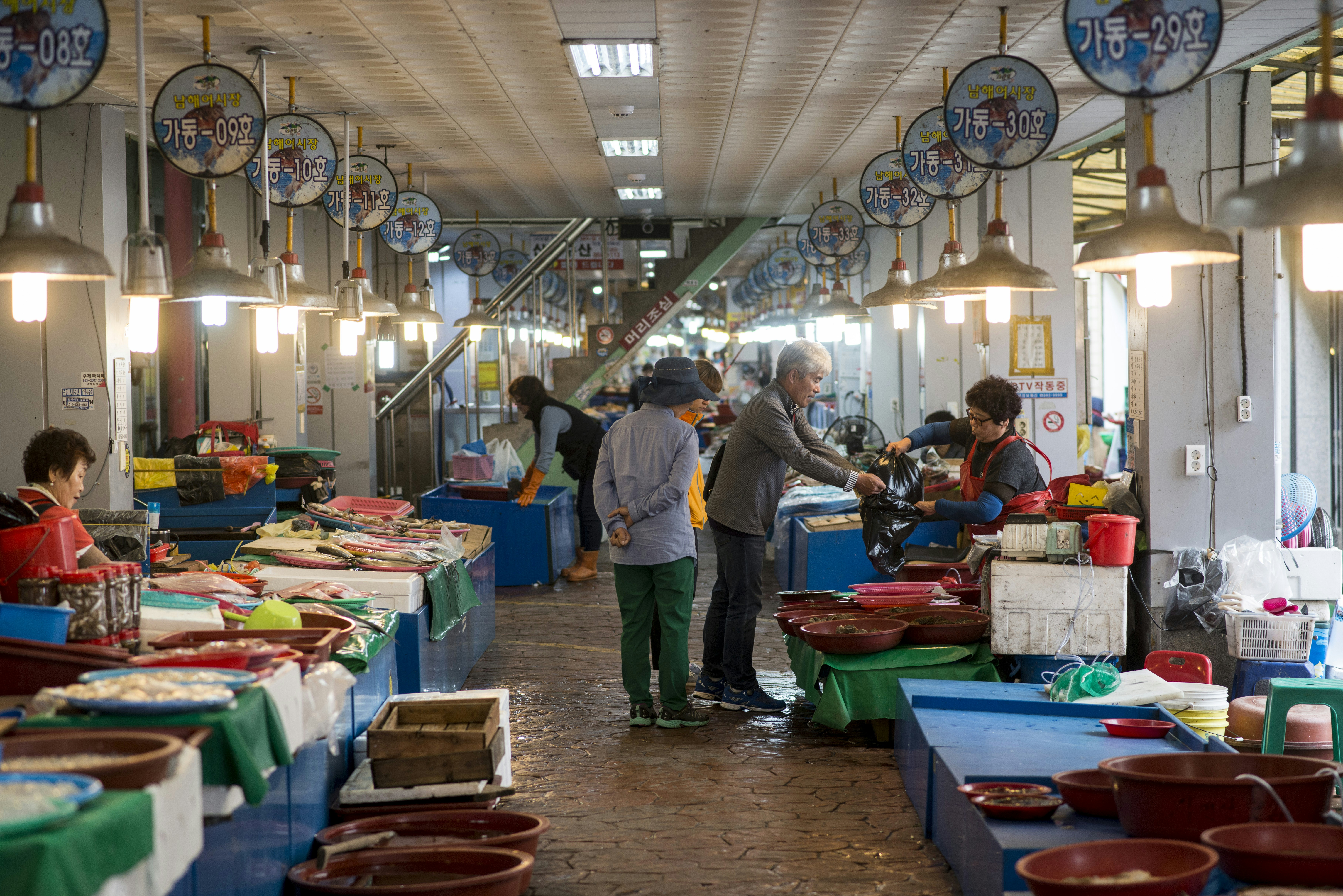 People shopping at an indoor fish market with many stalls