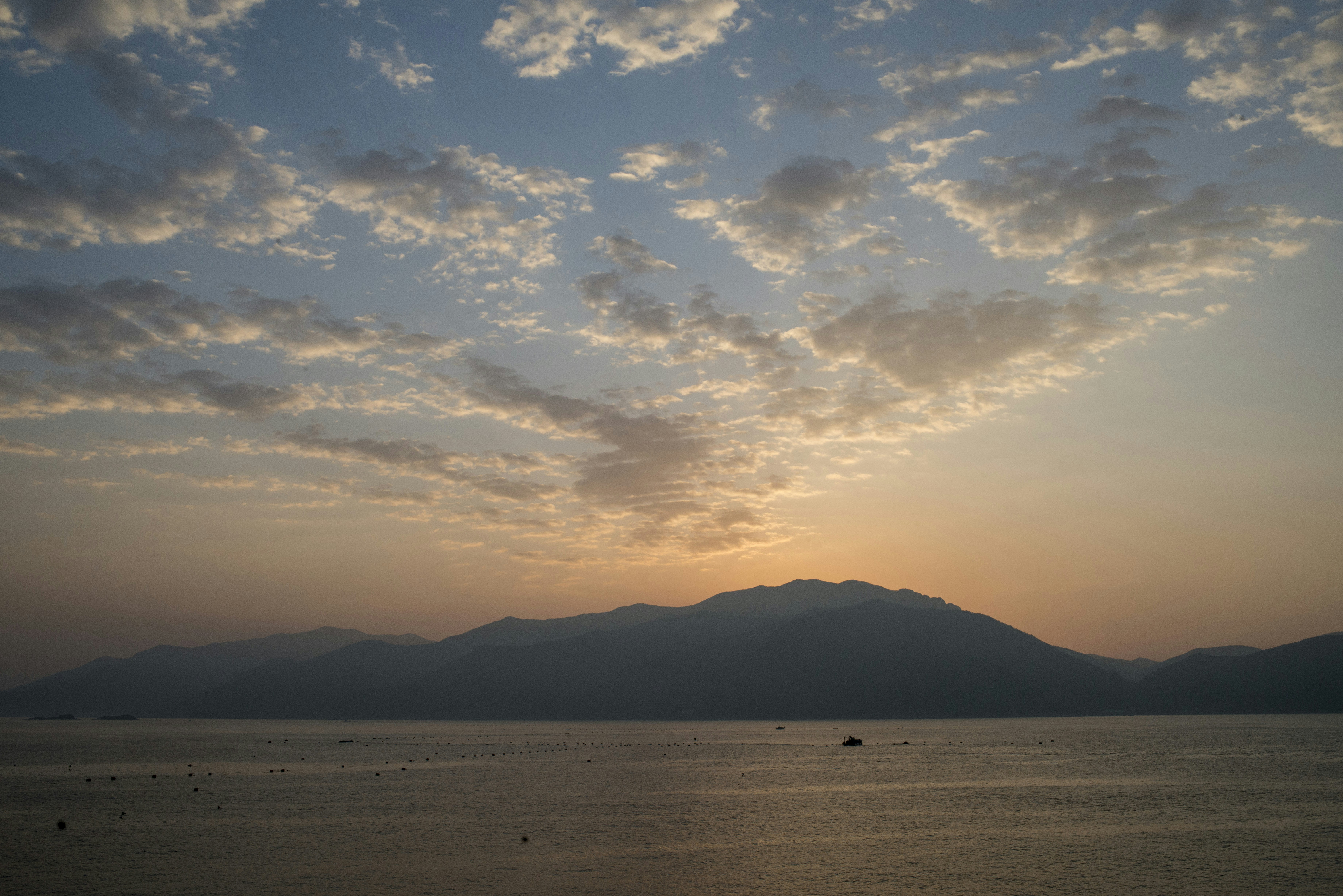 Sunset over a calm lake with mountains and clouds