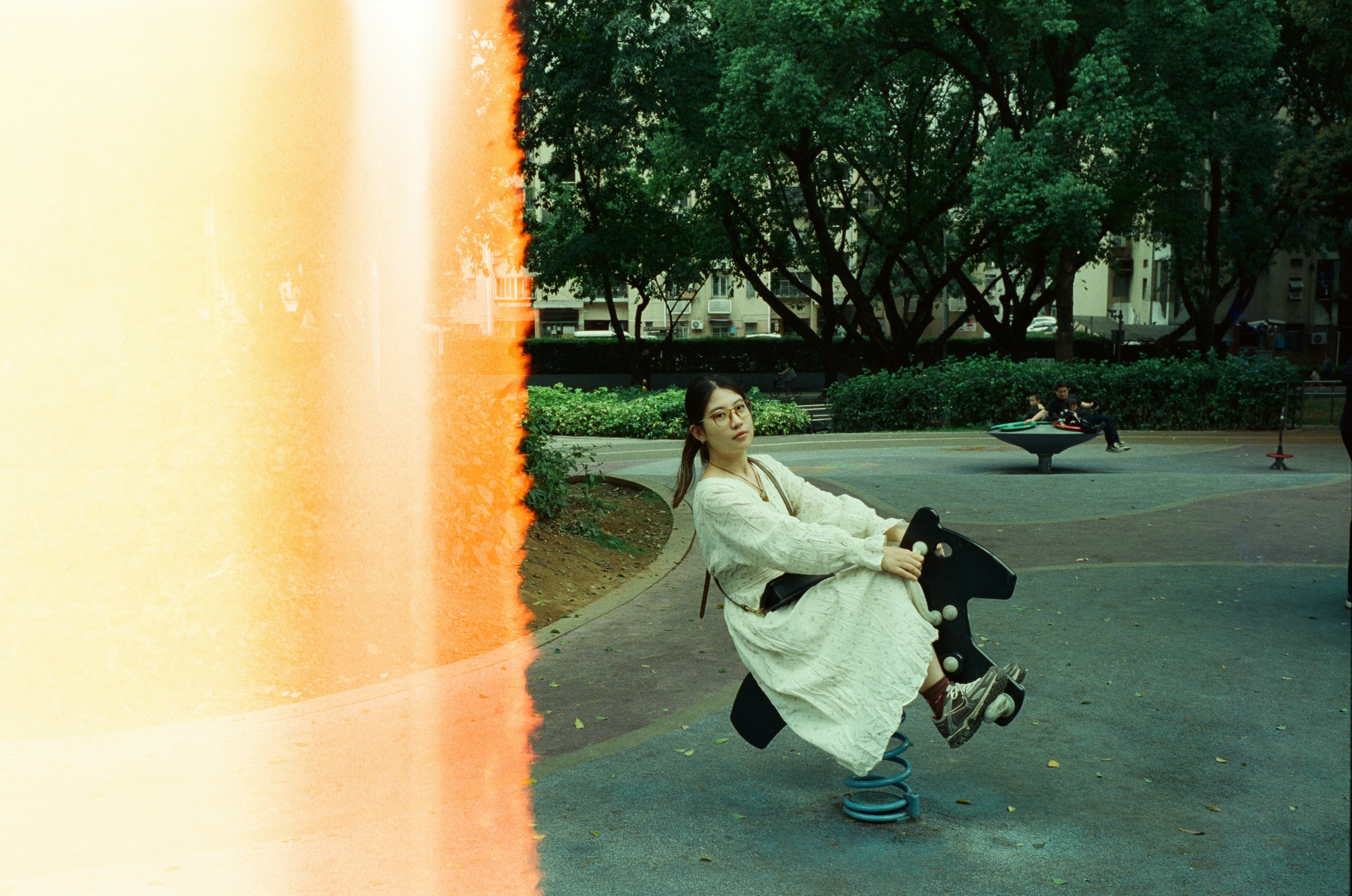 Woman on spring rider in park with orange light streak.