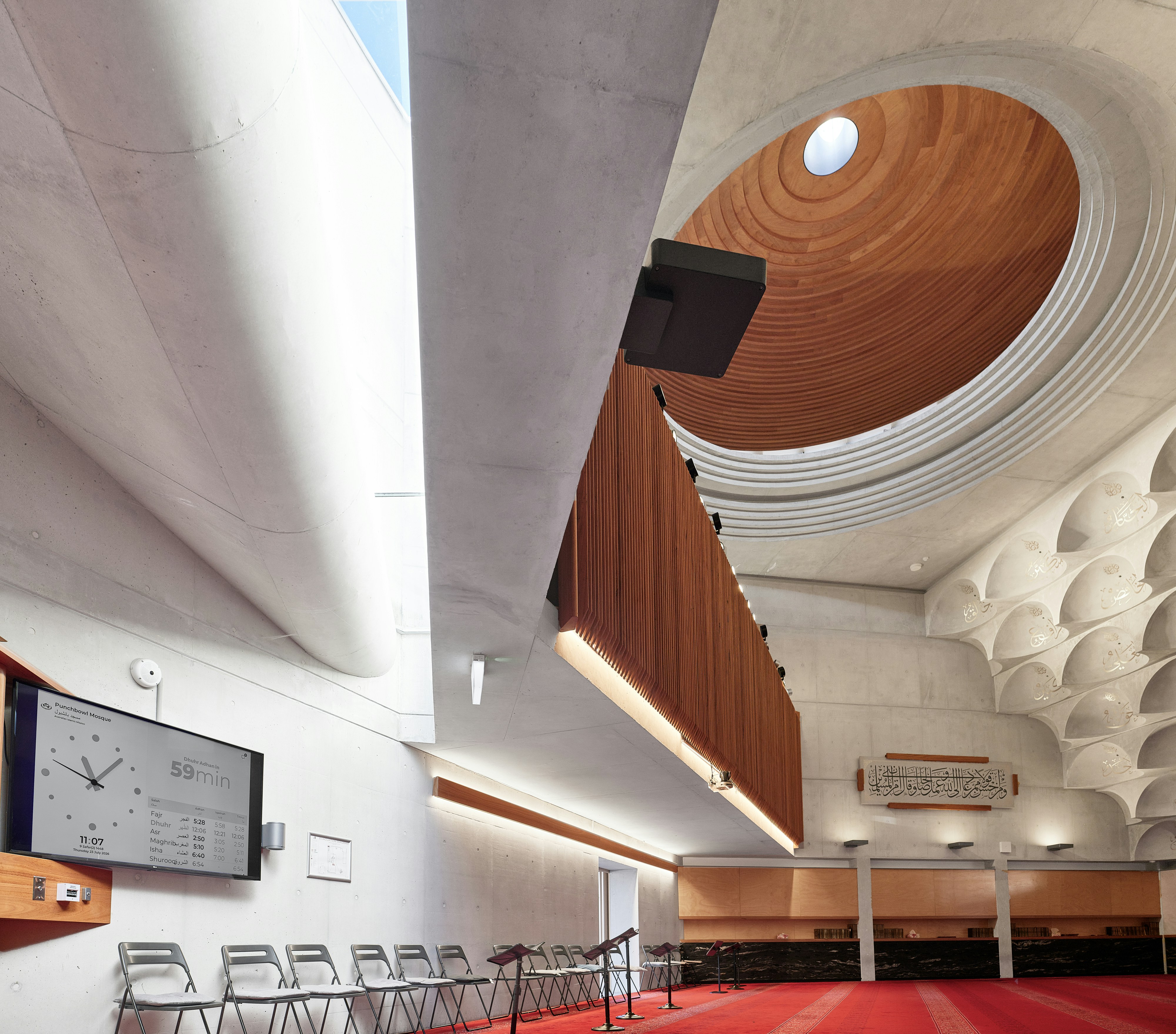 Contemporary mosque interior with a timber dome and quiet geometric light