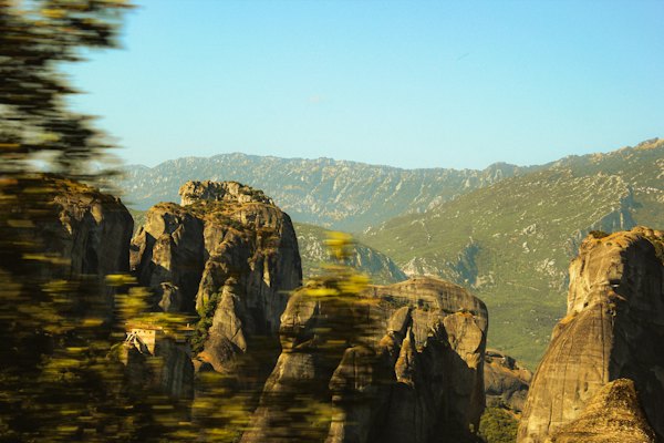 Rugged rock formations stand tall against green mountains — Meteora, Greece