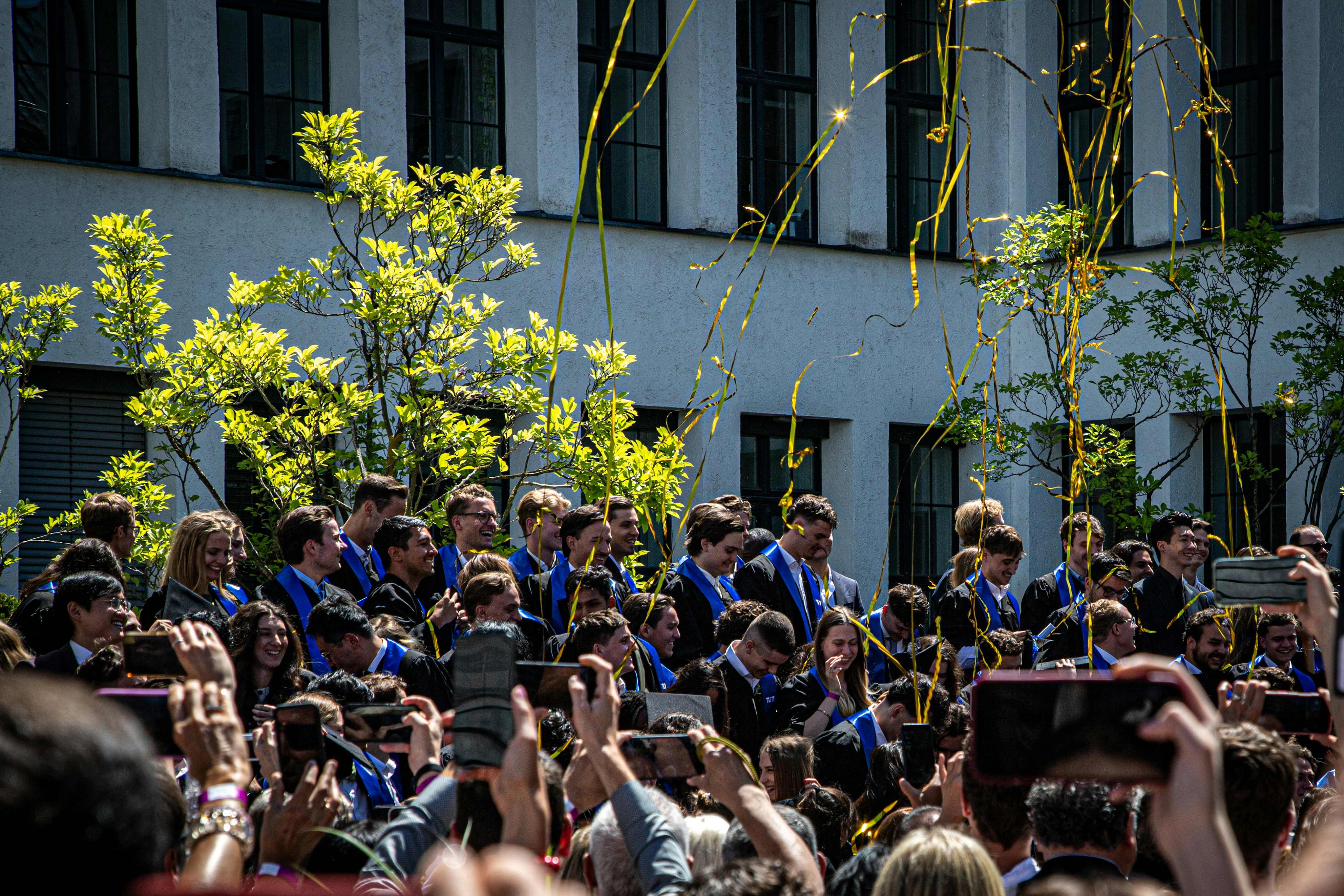 Graduates celebrating outdoors with yellow confetti falling