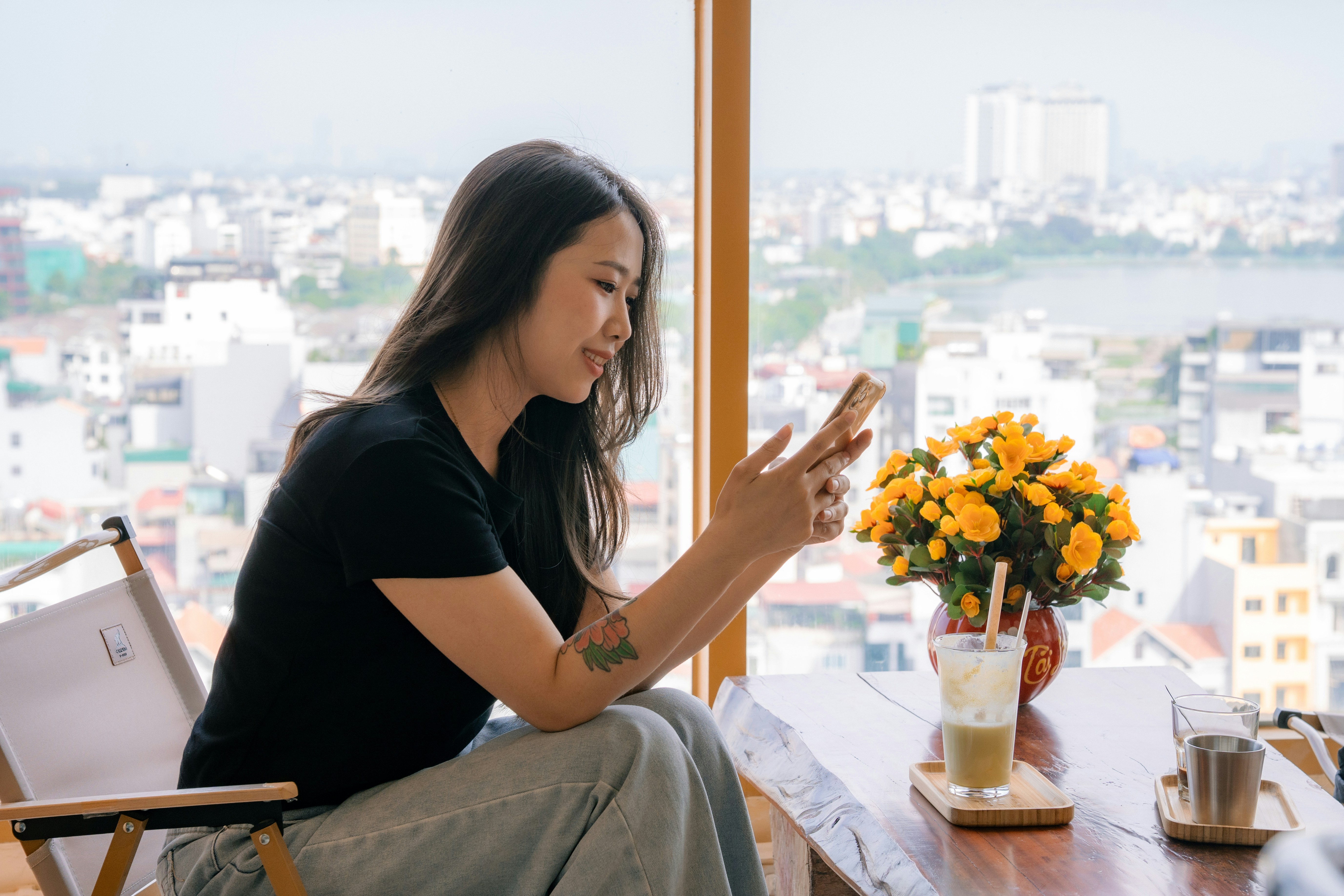 Woman holding a phone by a window, symbolising uncertainty about the future of a long-distance relationship