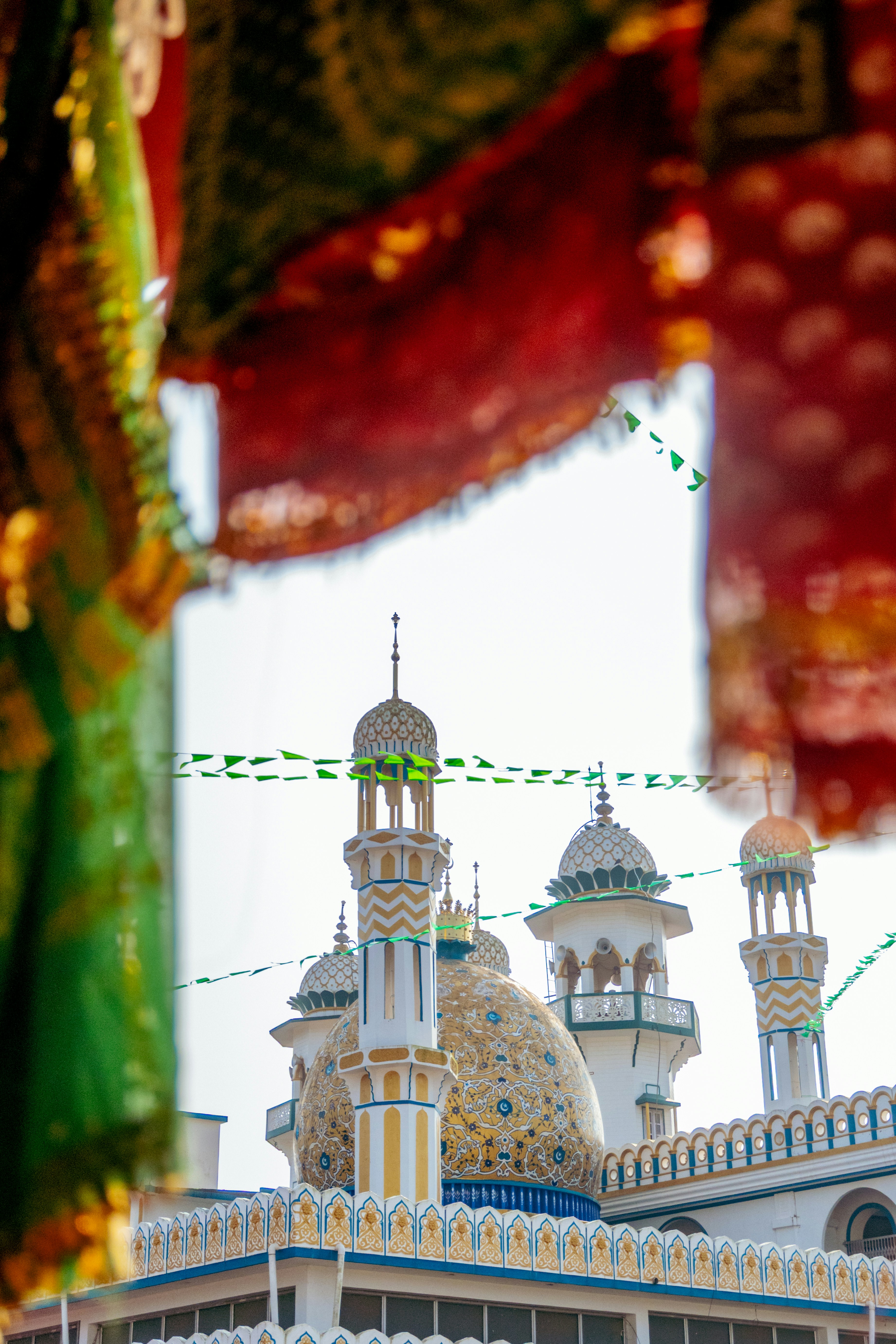Verzierte Moscheekuppeln und Minarette durch bunte Stoffe zu sehen.