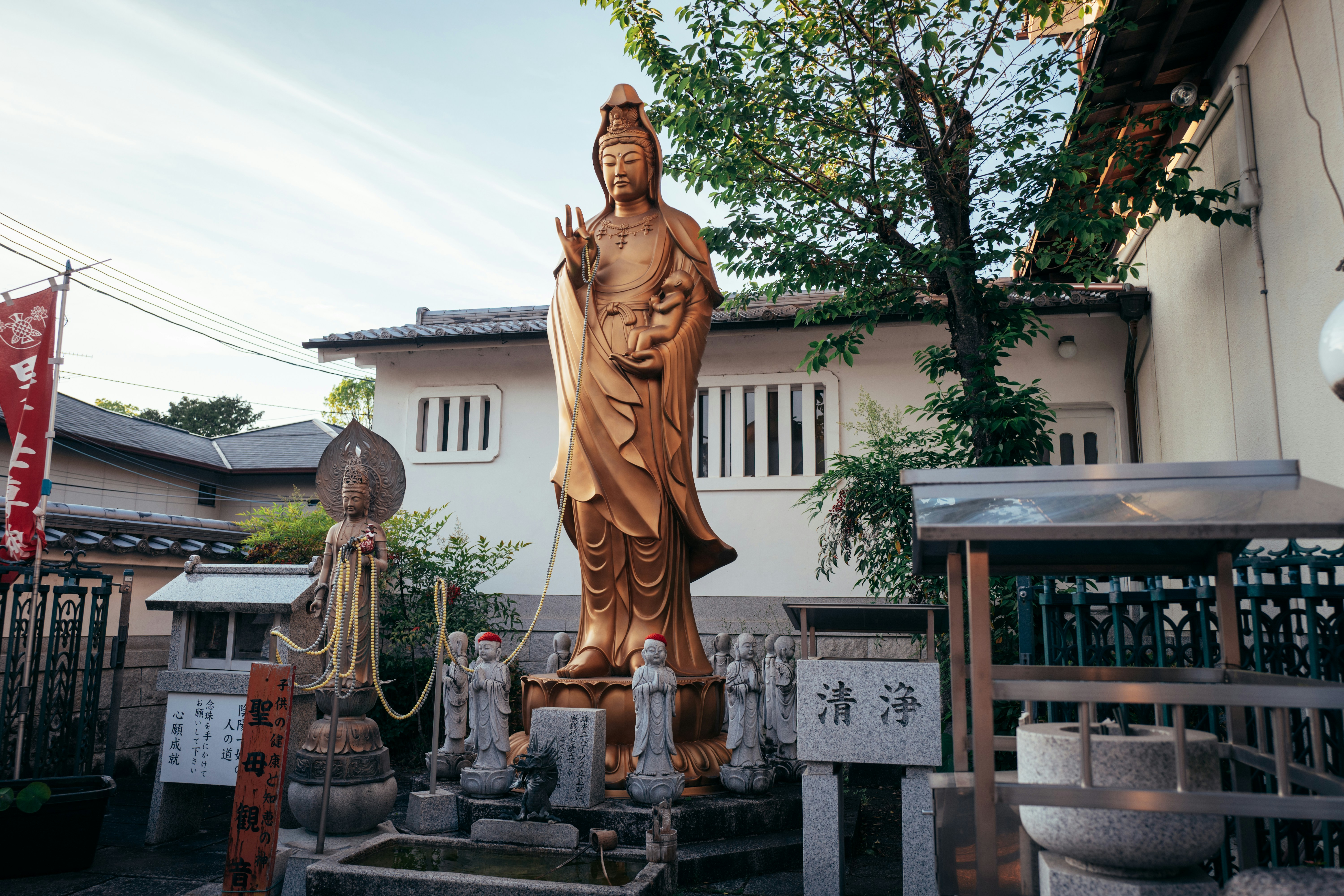 A tall golden buddhist statue stands in a temple courtyard