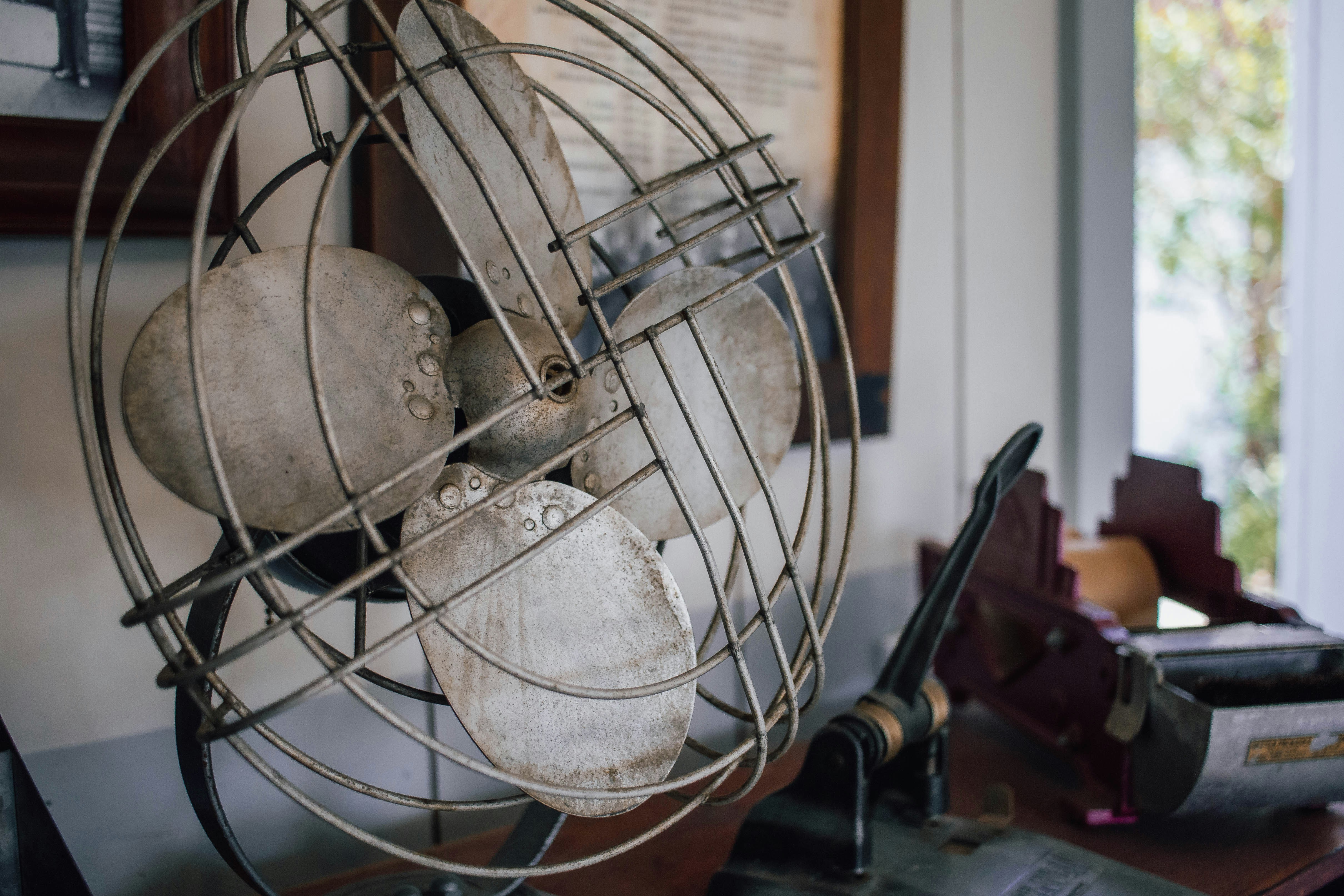 An old, dusty vintage electric fan on a table