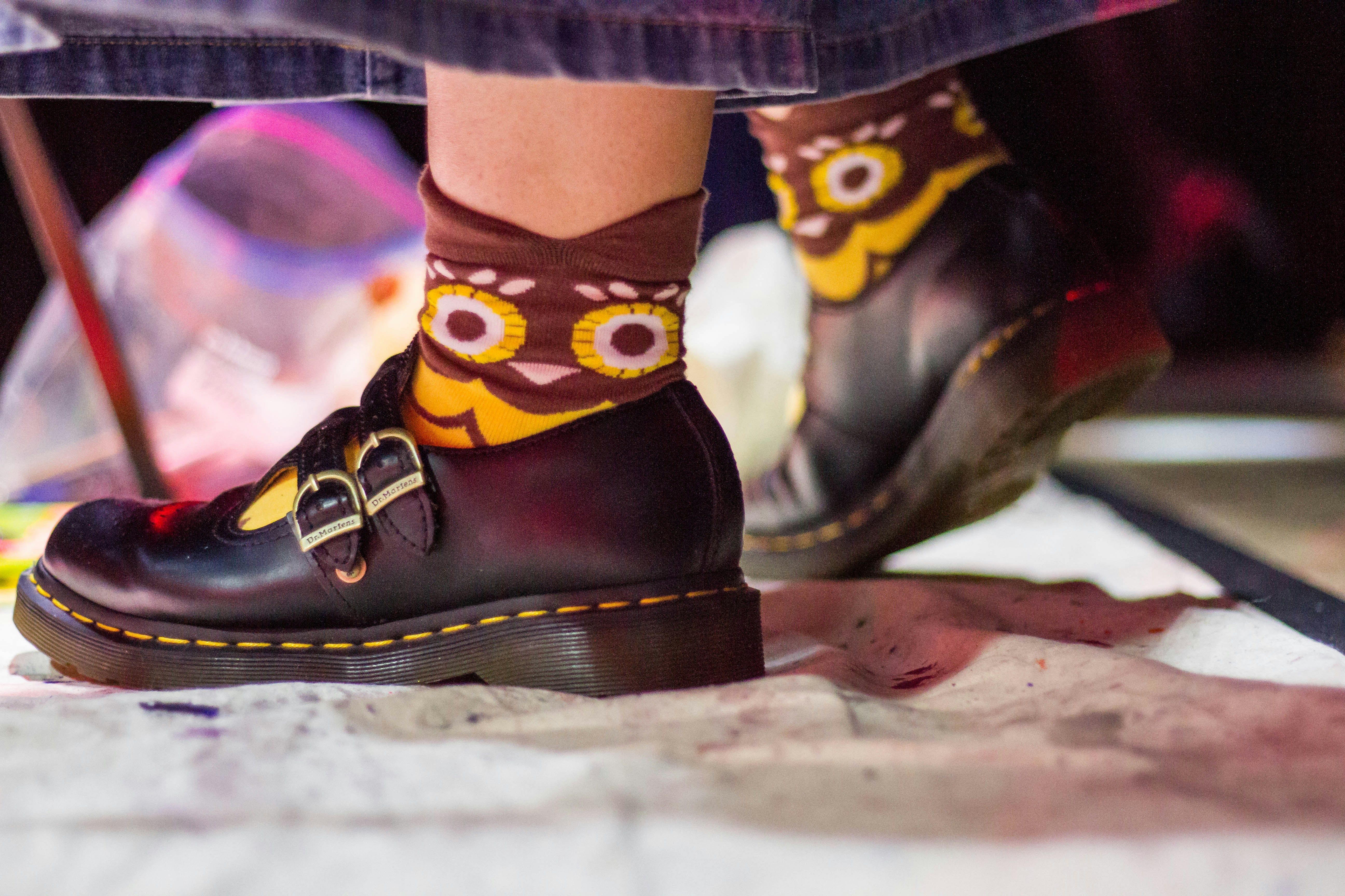 A person wearing dark shoes with buckles and owl-faced socks