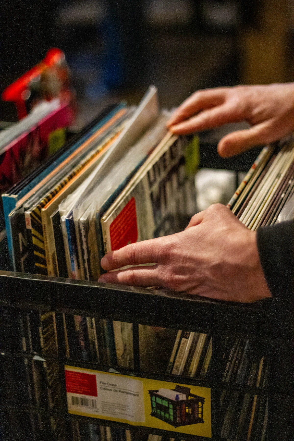Hands flipping through a crate of vinyl records