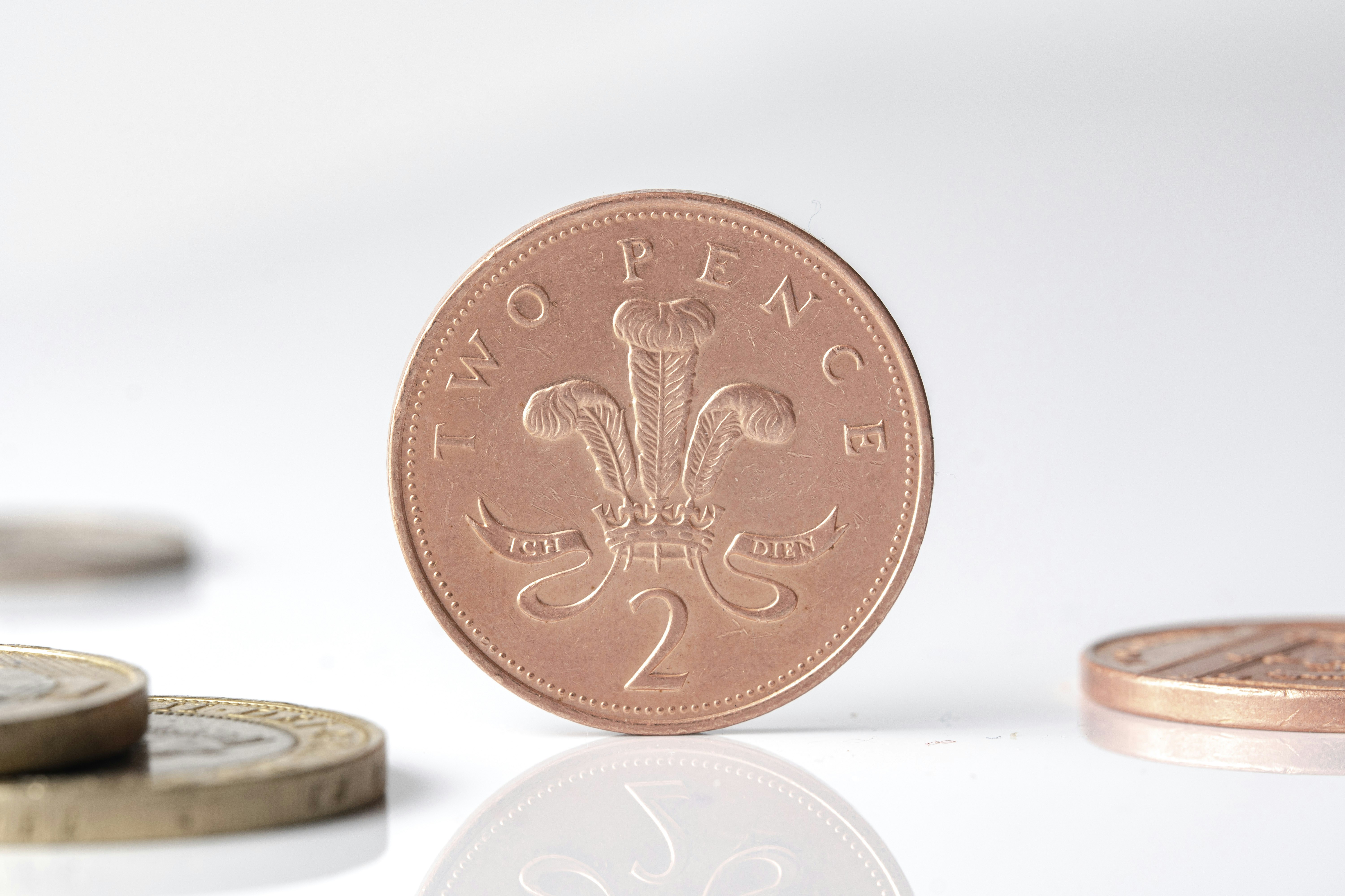 British two pence coin standing upright with blurred coins.