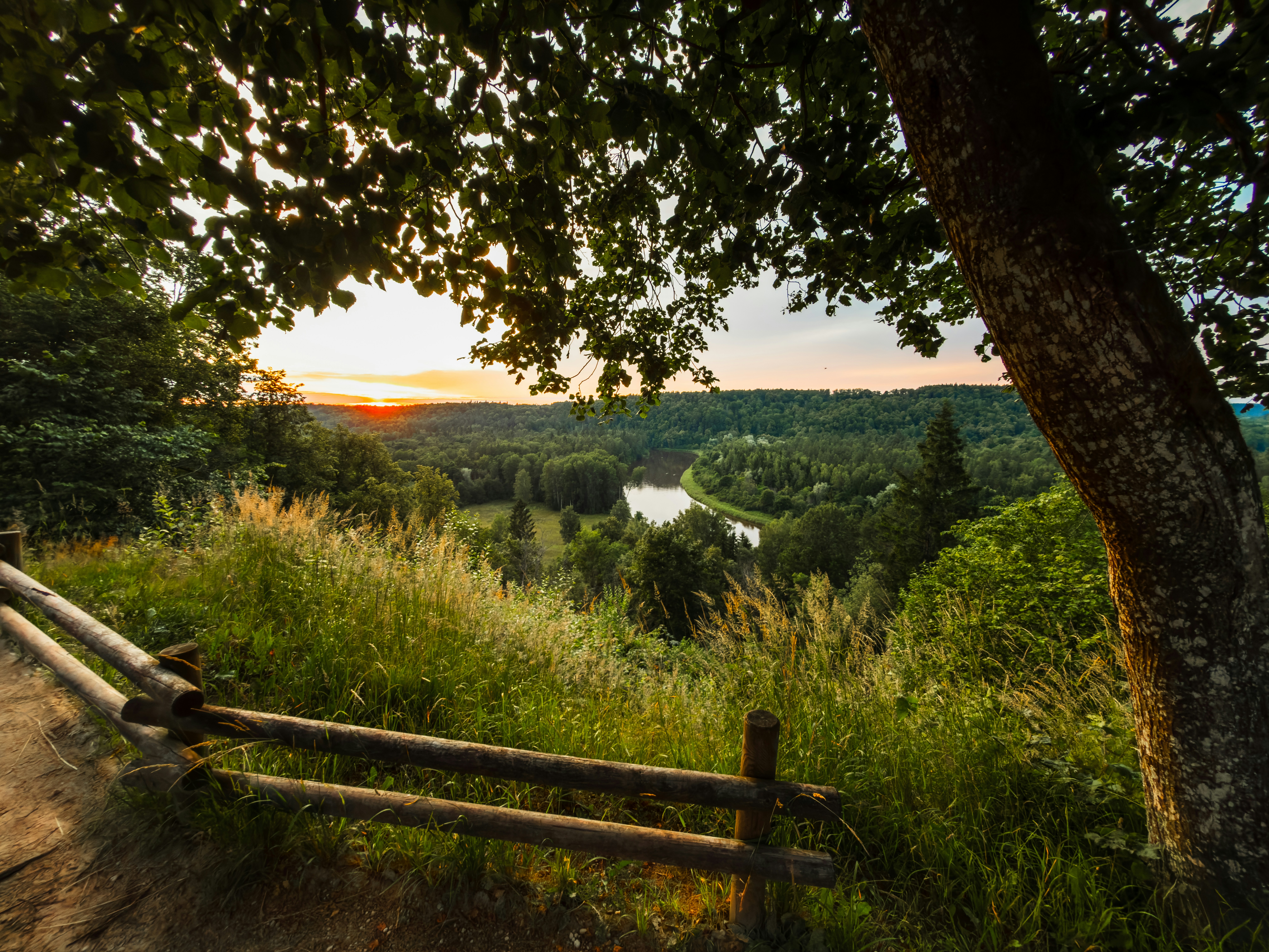 Sunset over a lush valley with a winding river.
