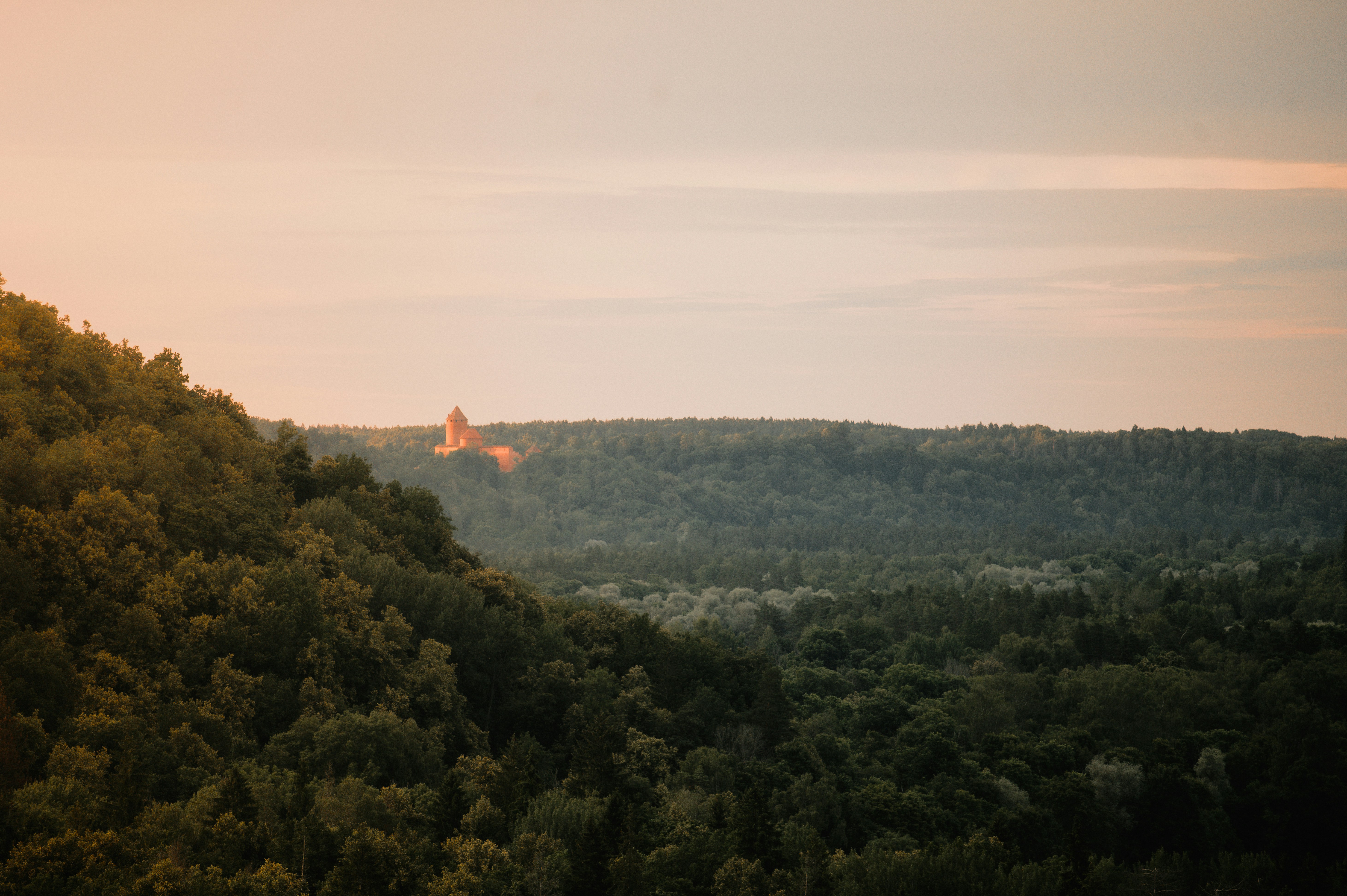 Sunset over forested hills with a distant castle.