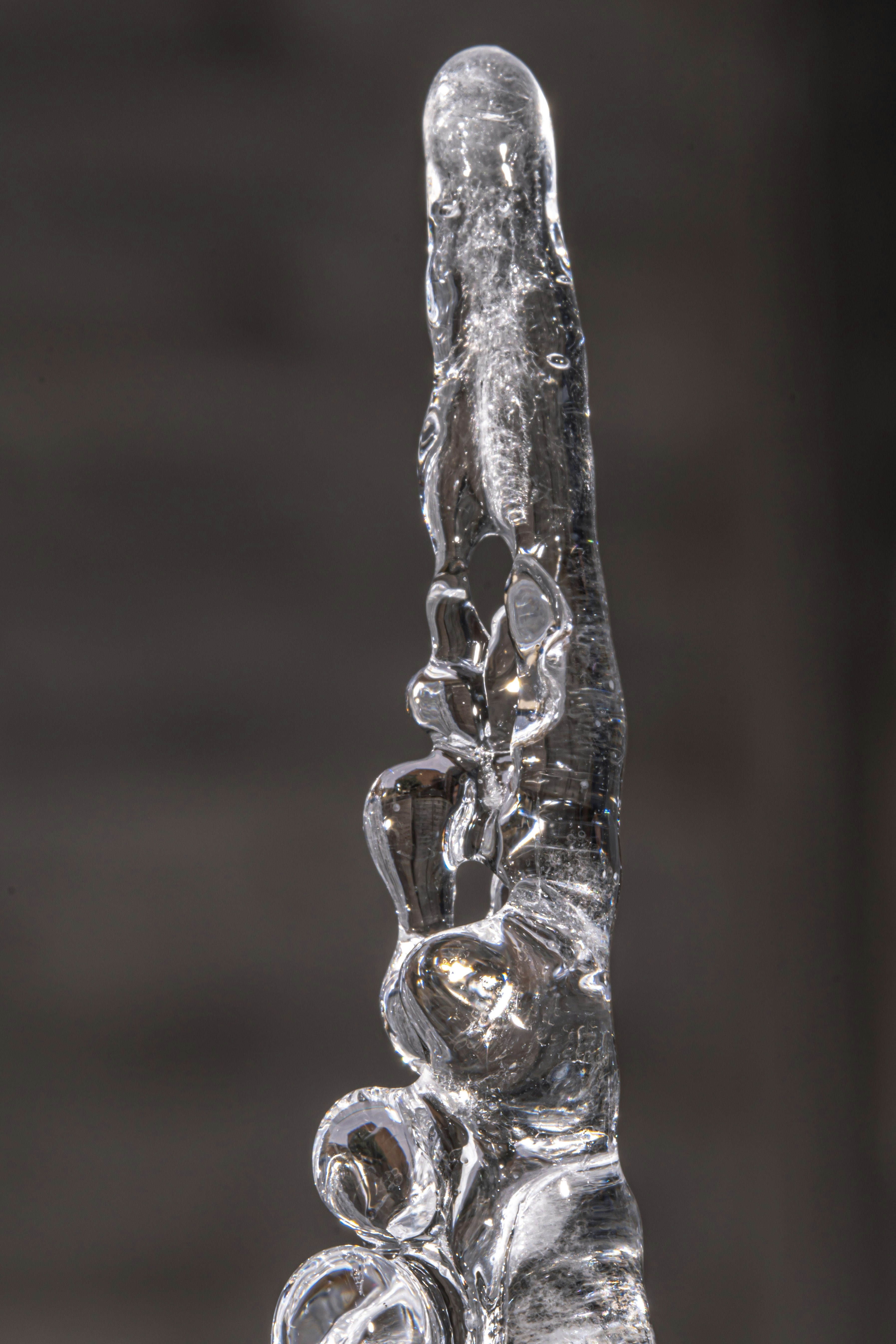 A clear, glistening icicle against a dark background.