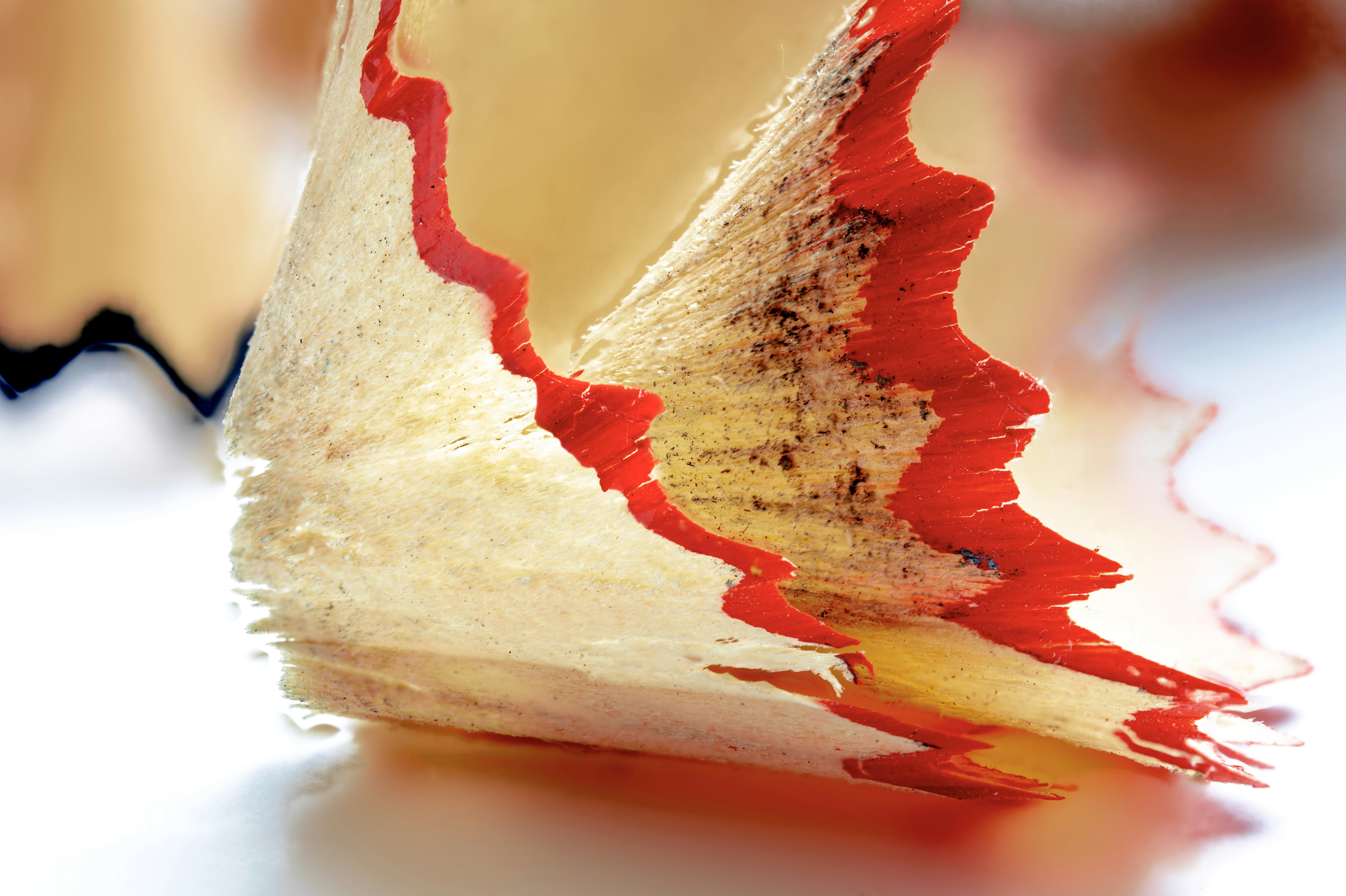 Red pencil shaving curls on a light surface