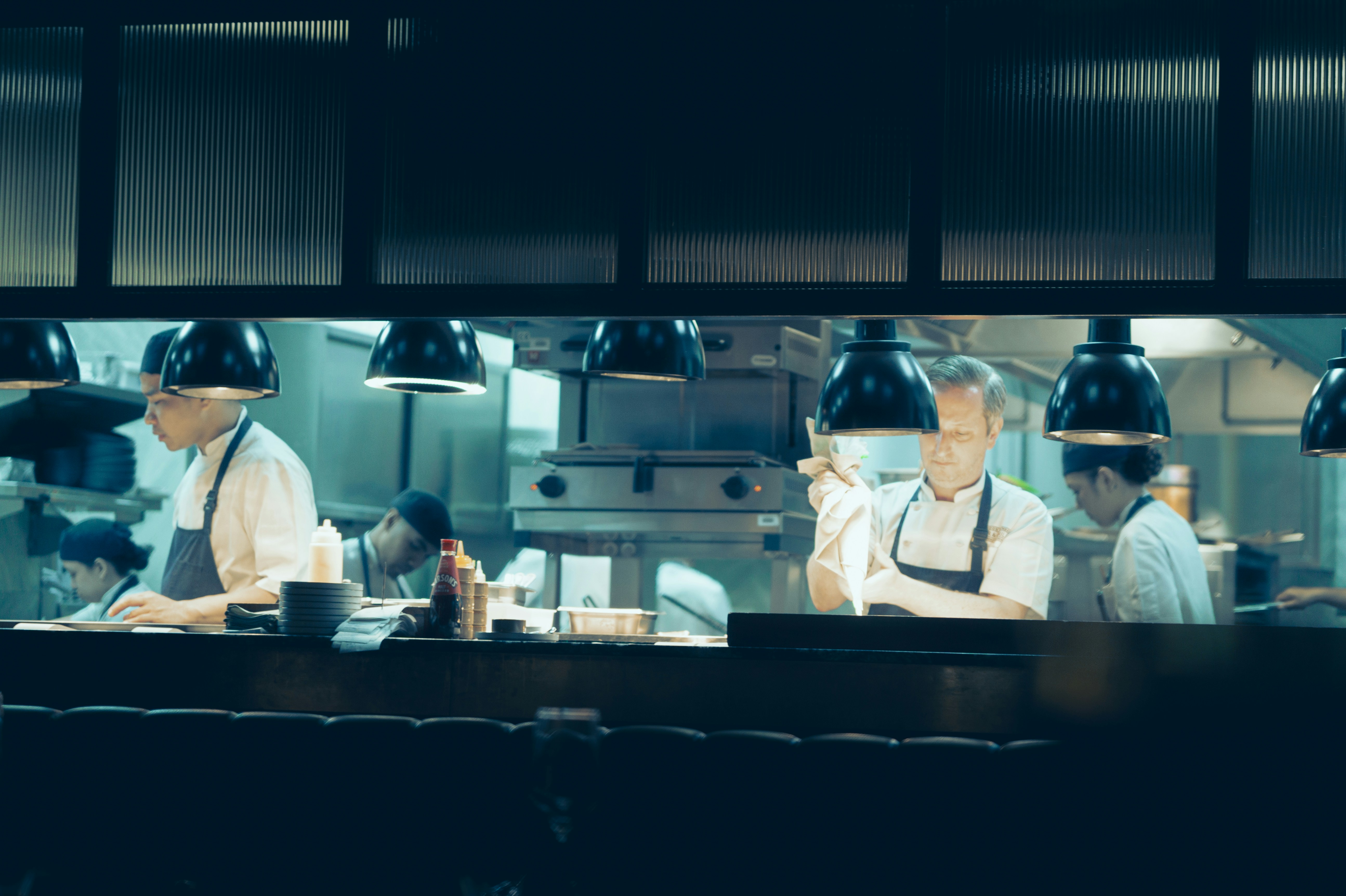 Professional chefs preparing food in a dark kitchen.