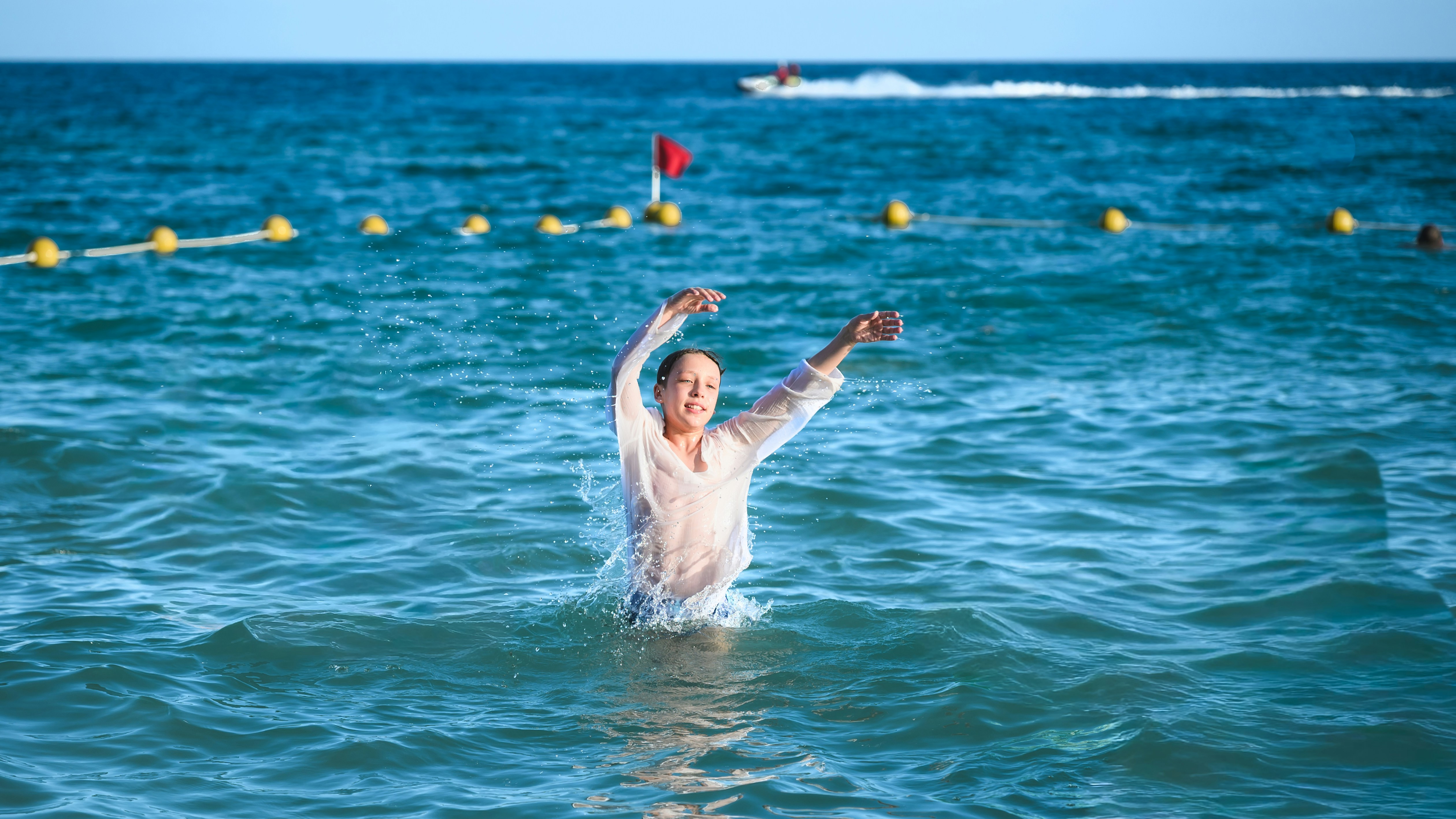 Uma mulher se diverte no oceano azul com os braços erguidos