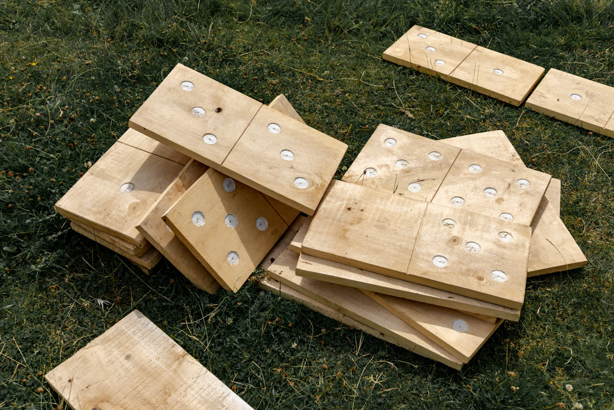 Wooden boards with white inserts stacked on green grass