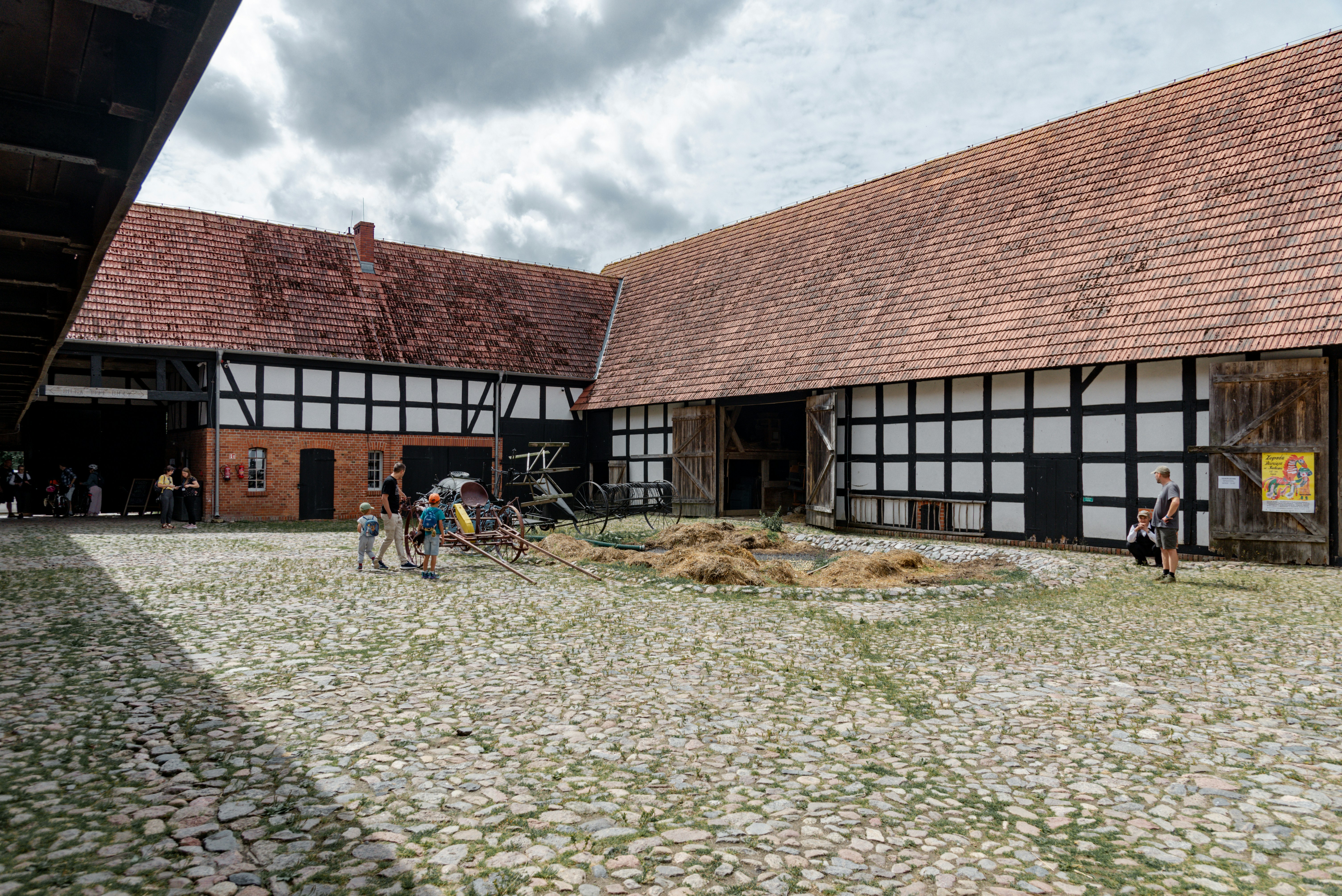 People gather in a historic cobblestone courtyard surrounded by barns - historic barns