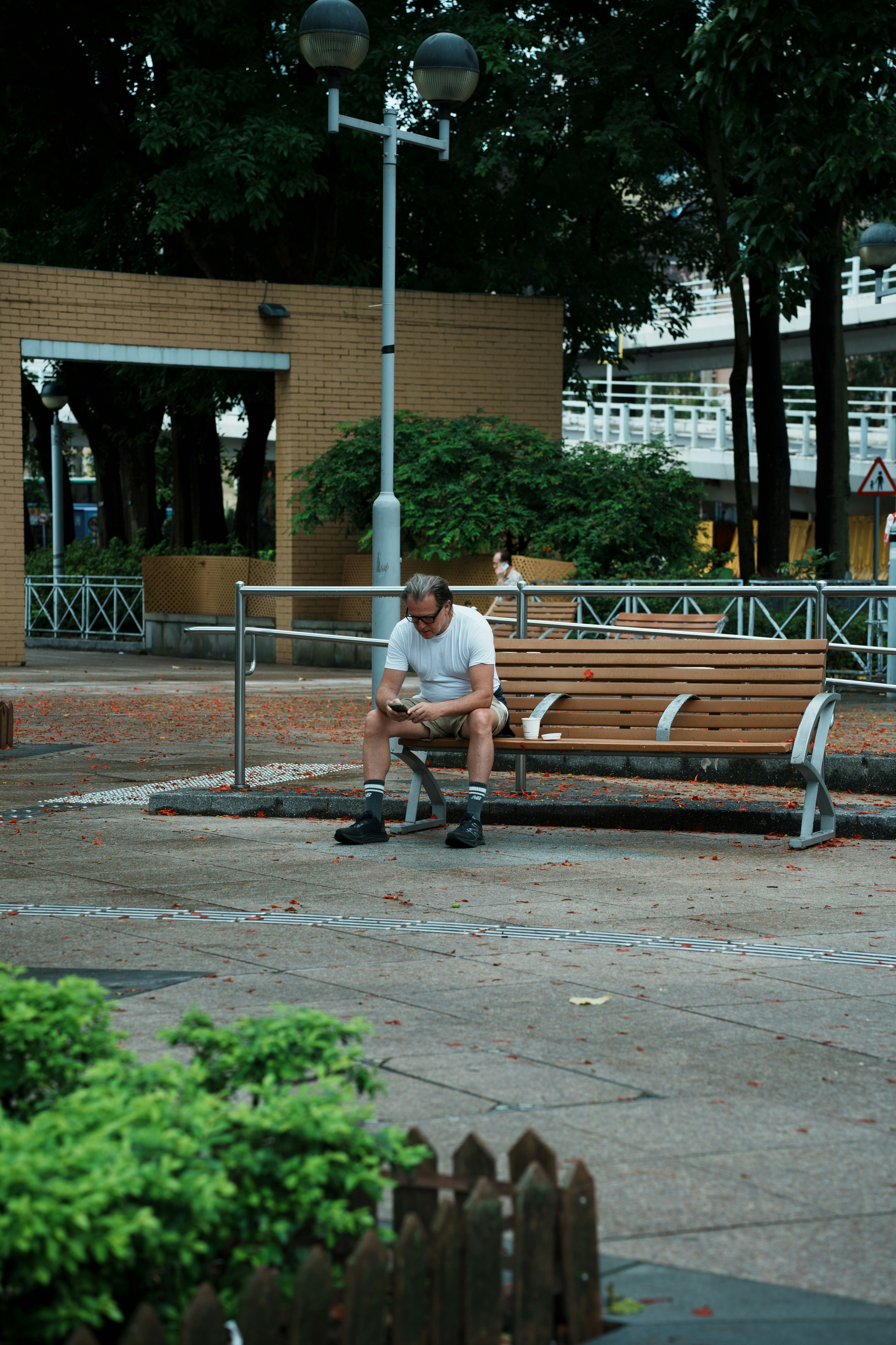 Bearded man sits on a wooden bench in a park.