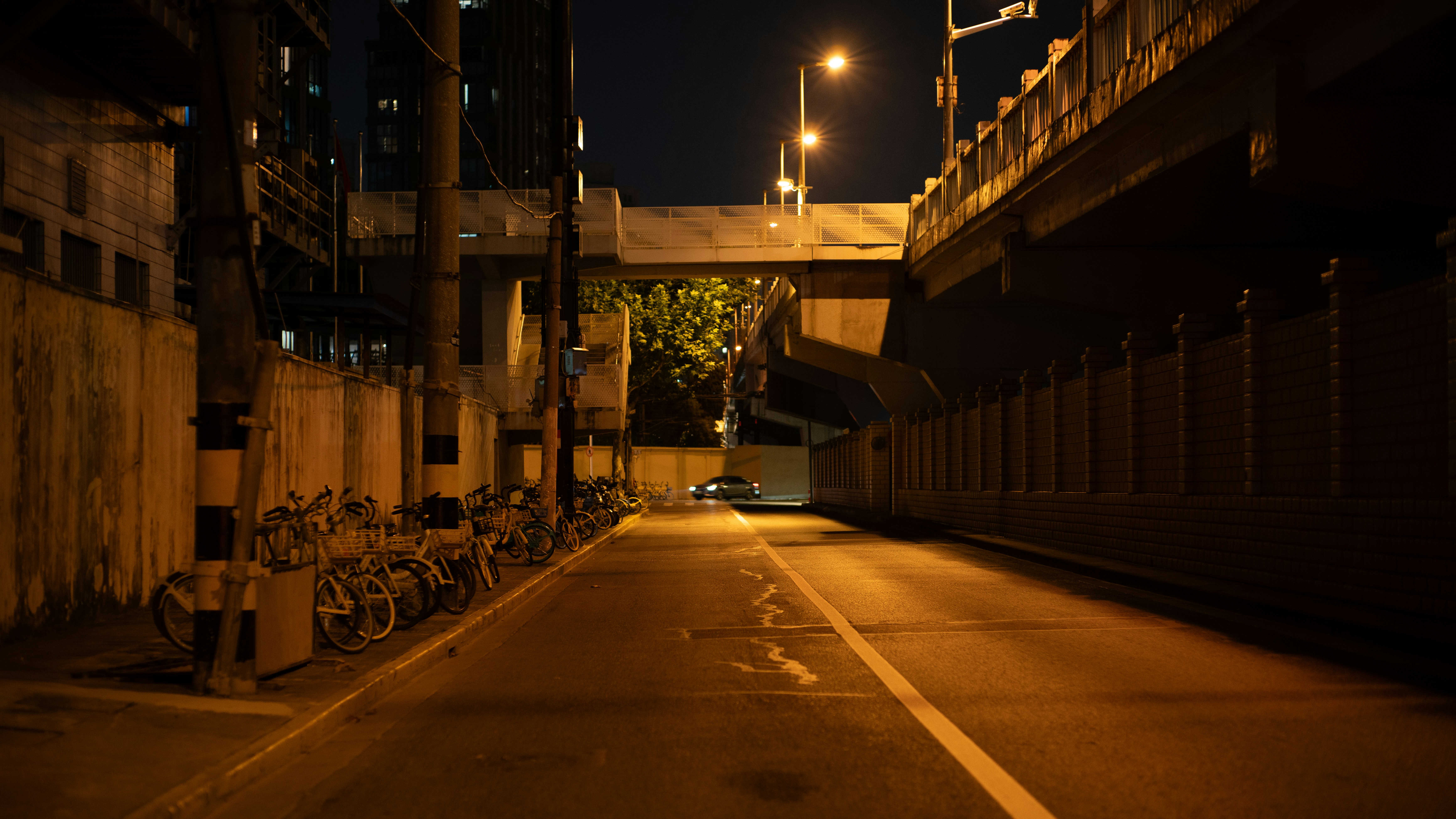 An empty street at night under a concrete overpass.