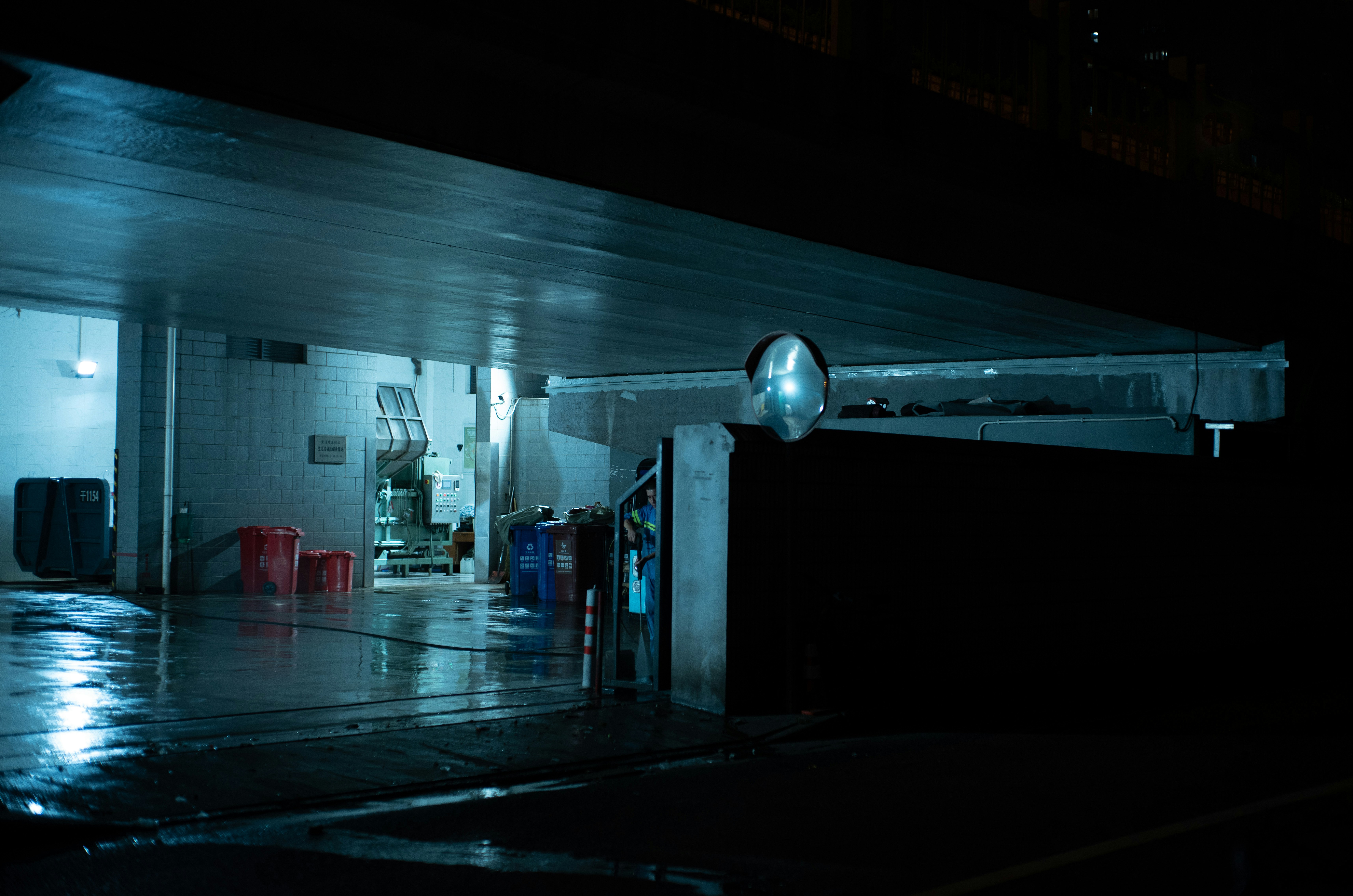 Dark, wet industrial building with interior light at night.