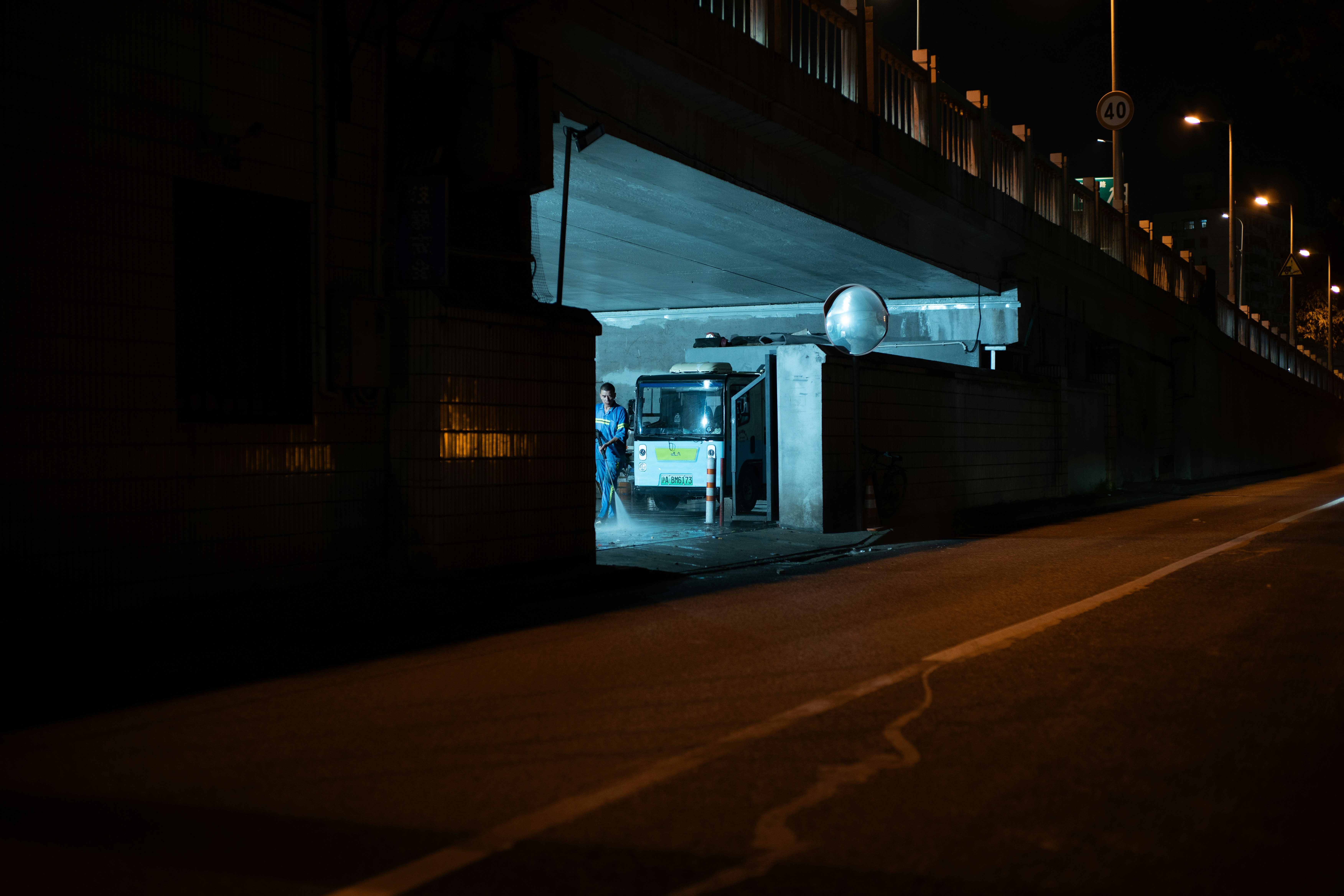 A small vehicle parked under a dark bridge at night.