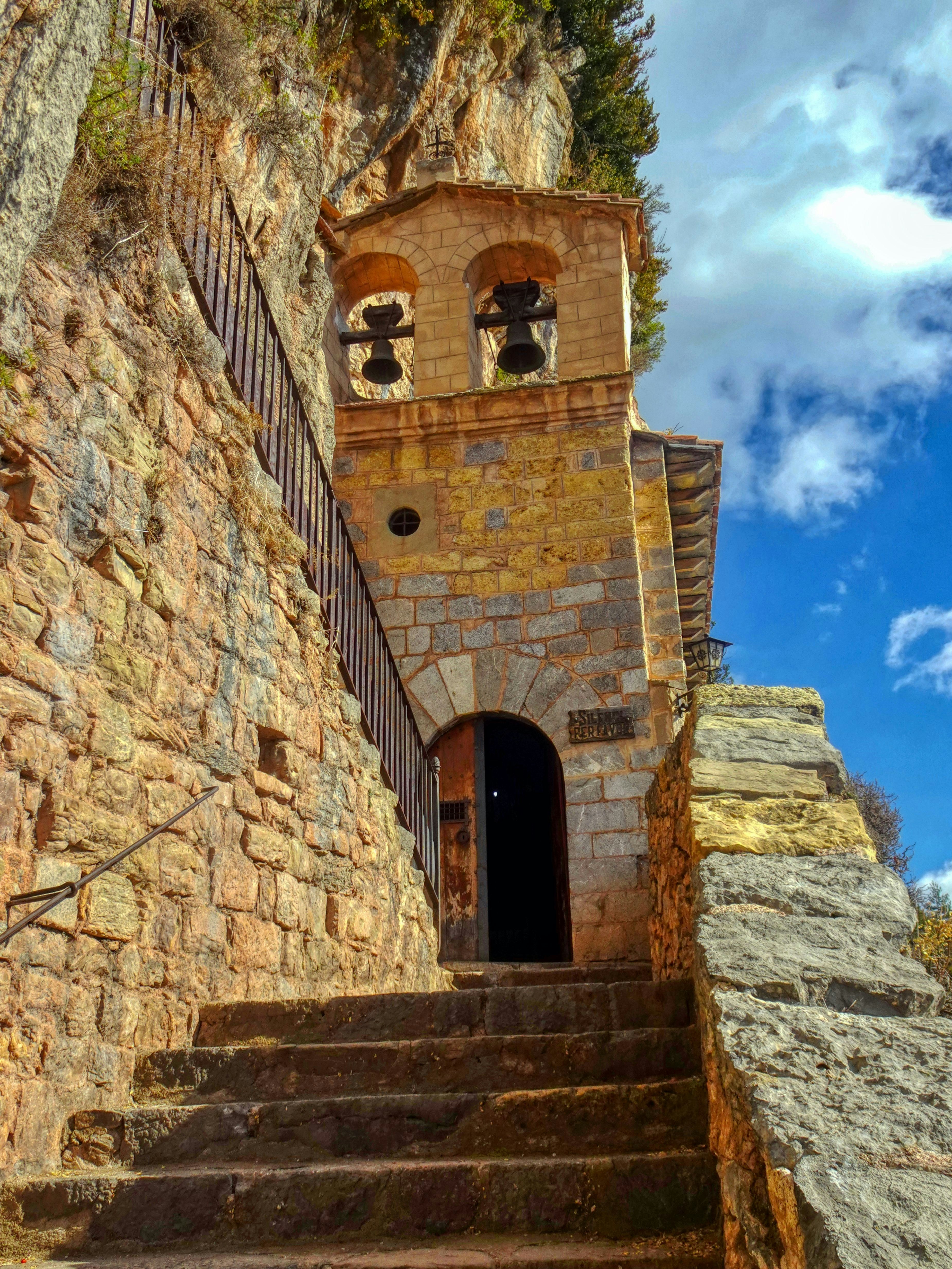 Historic stone hermitage nestled in a cliff with steps.