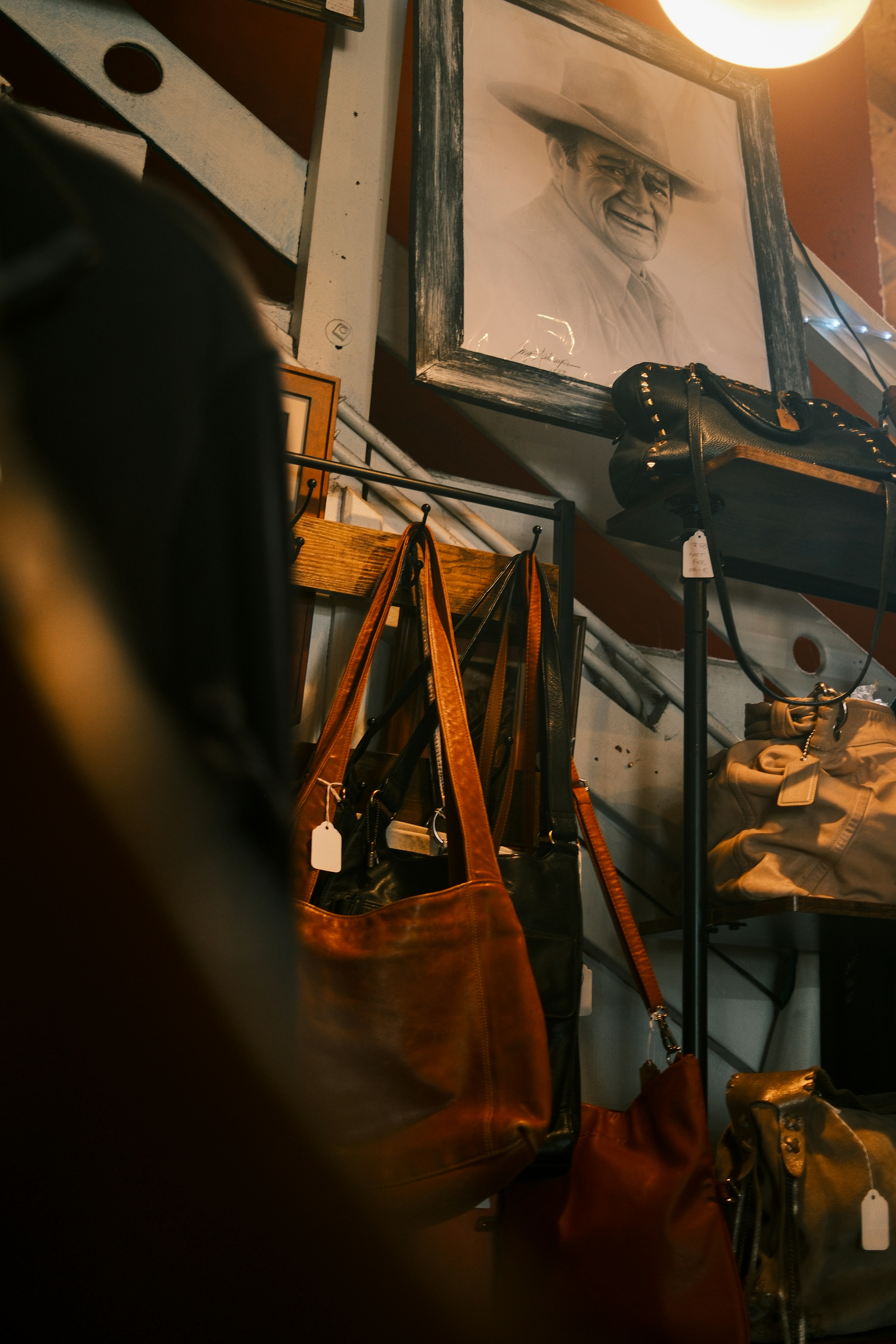 Leather bags hanging on a rack with a framed portrait.