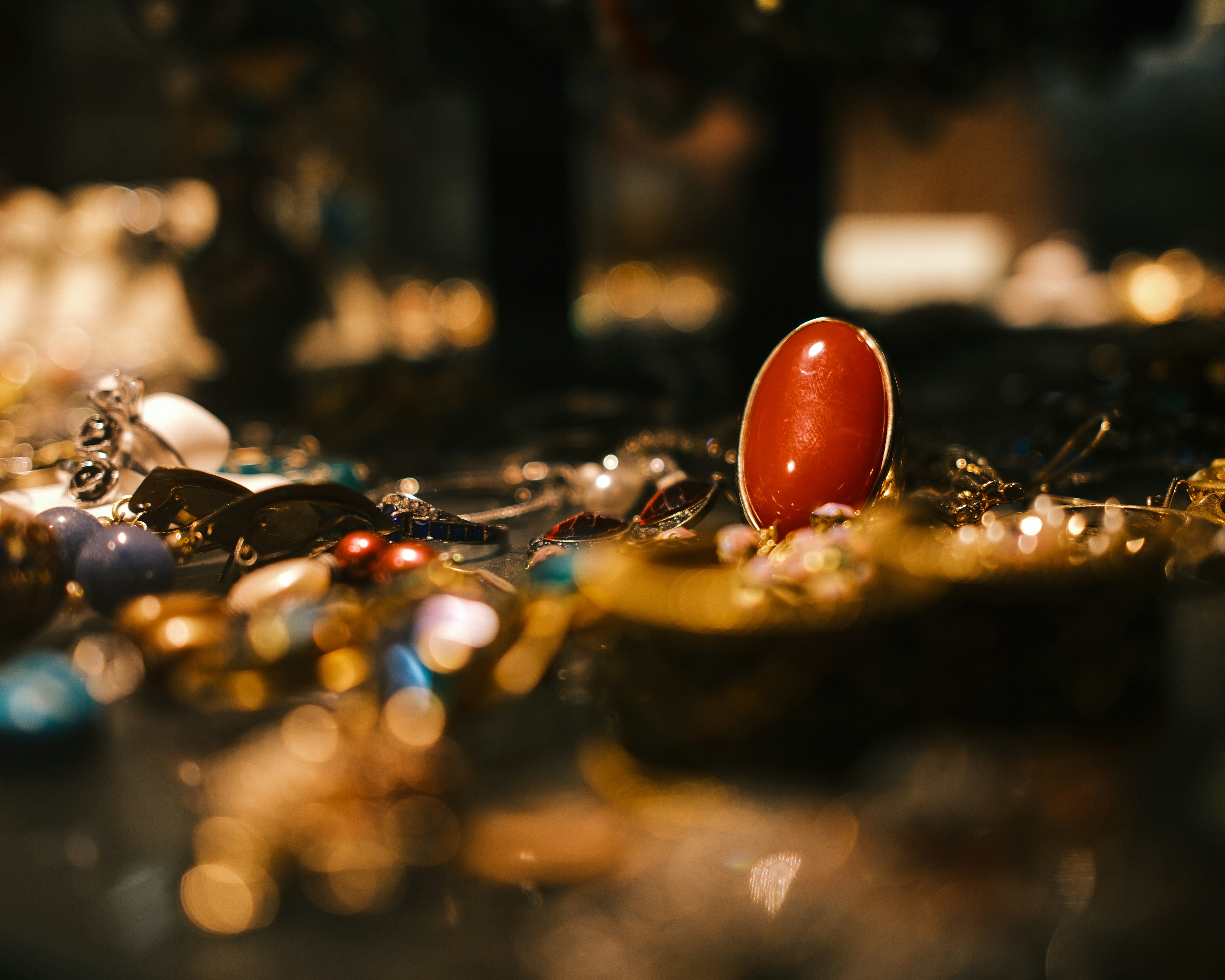A red oval object stands amidst sparkling jewelry.