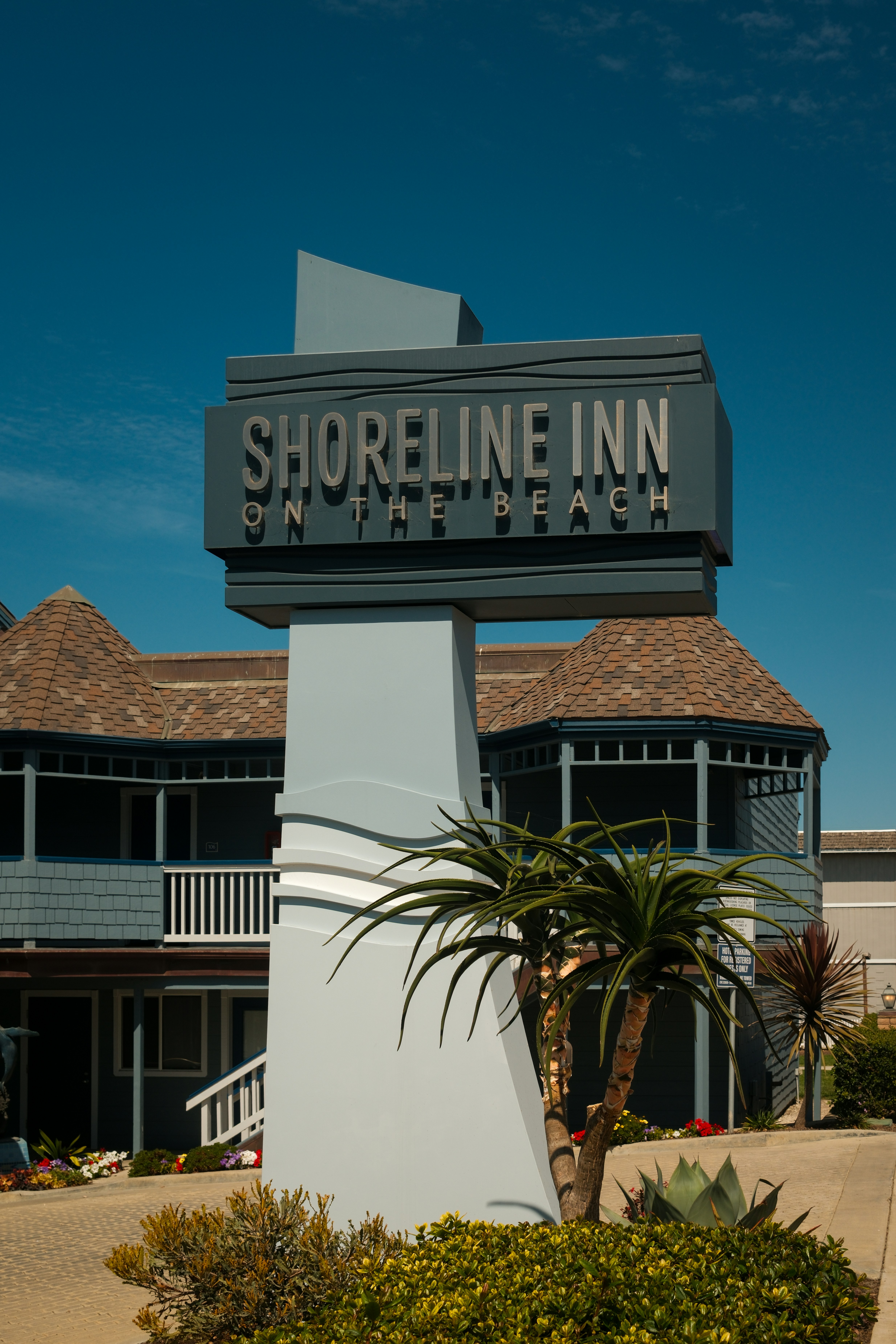 Shoreline inn on the beach sign with building and plants.