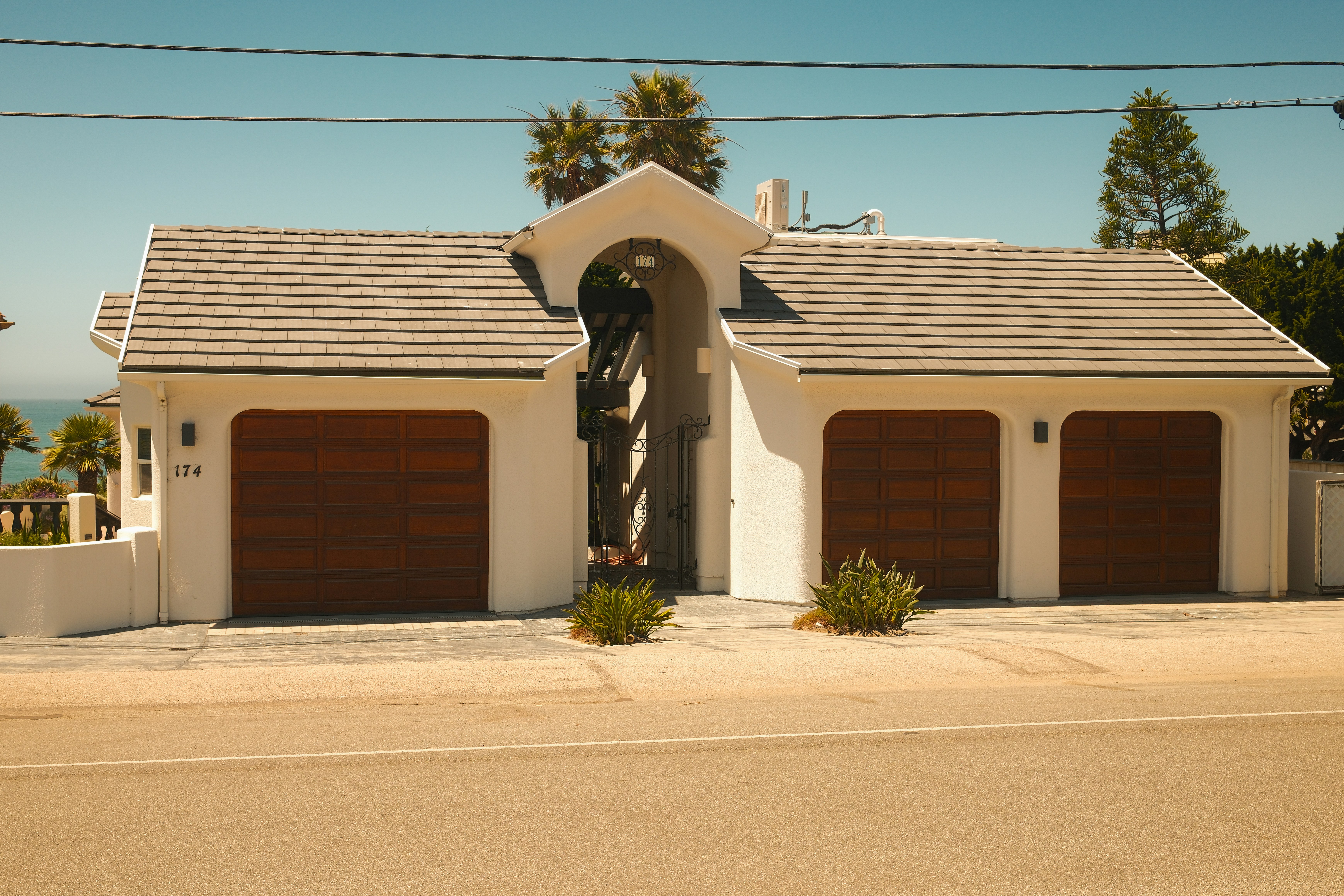 Coastal white house with two garage doors and arched entry.
