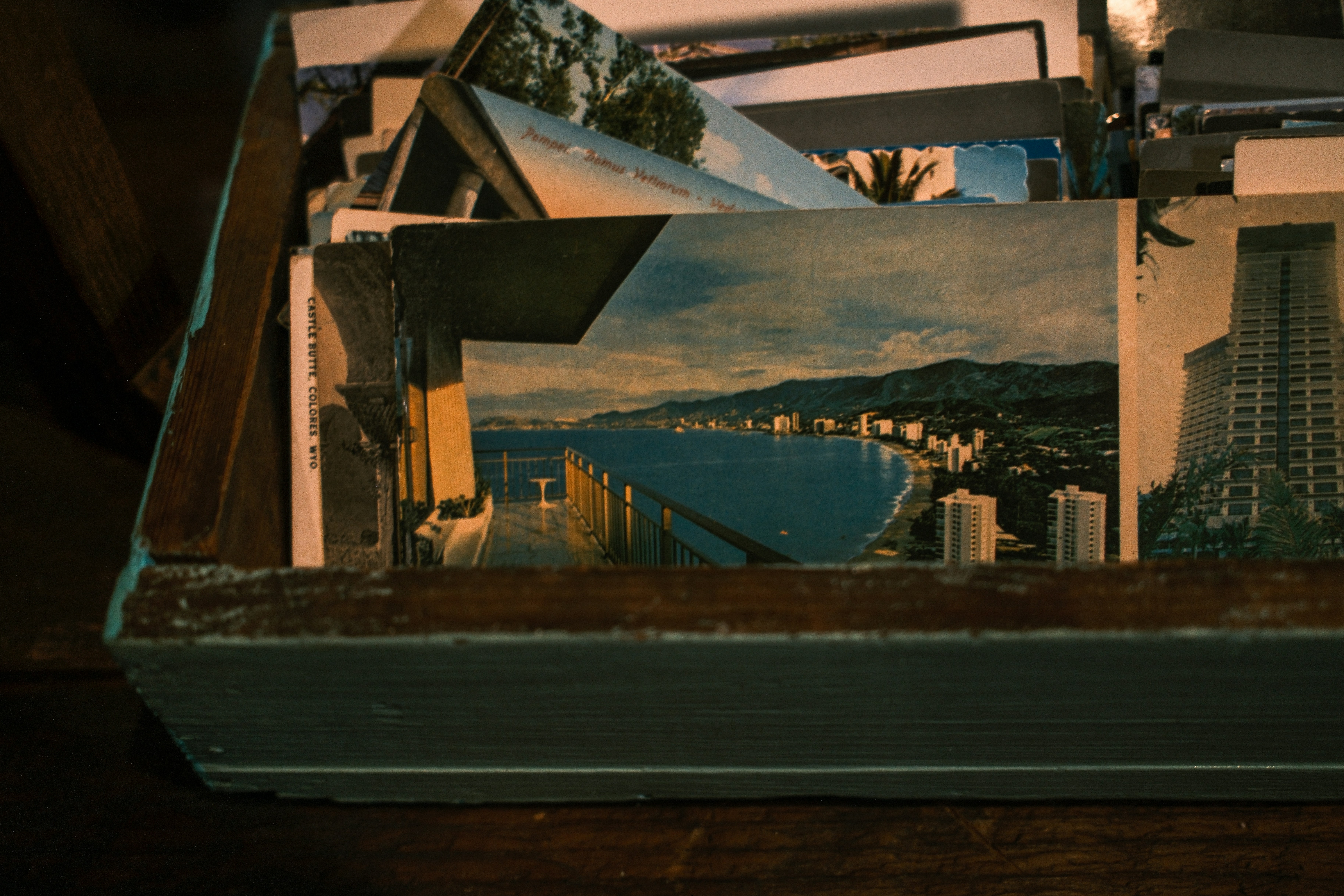 Old postcards in a wooden box, featuring a coastal city.
