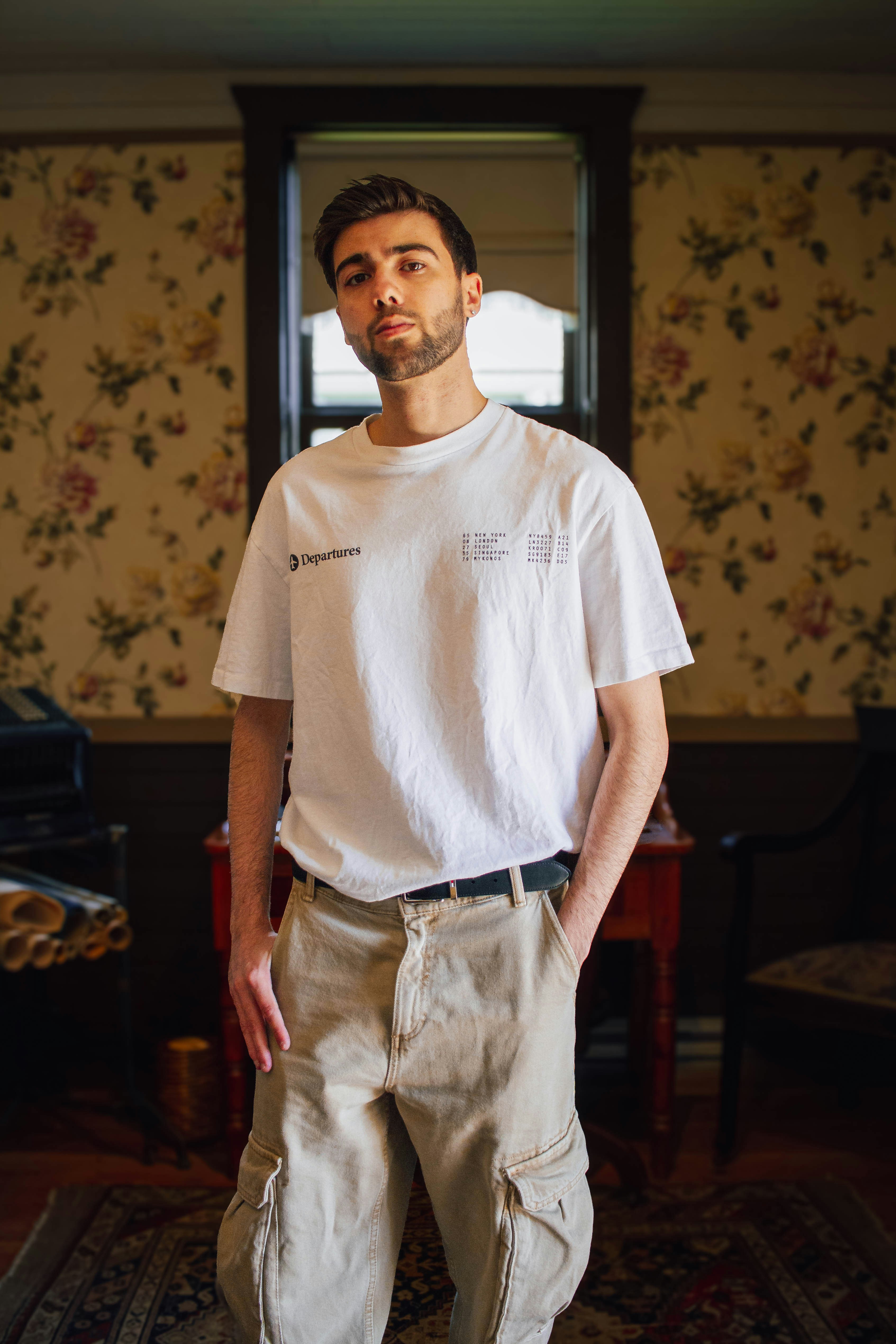 Young man standing in a room with floral wallpaper