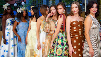 Eight women in colorful dresses standing together