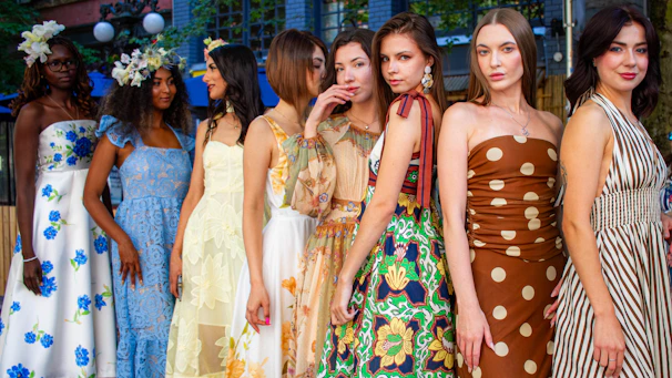 Eight women in colorful dresses standing together