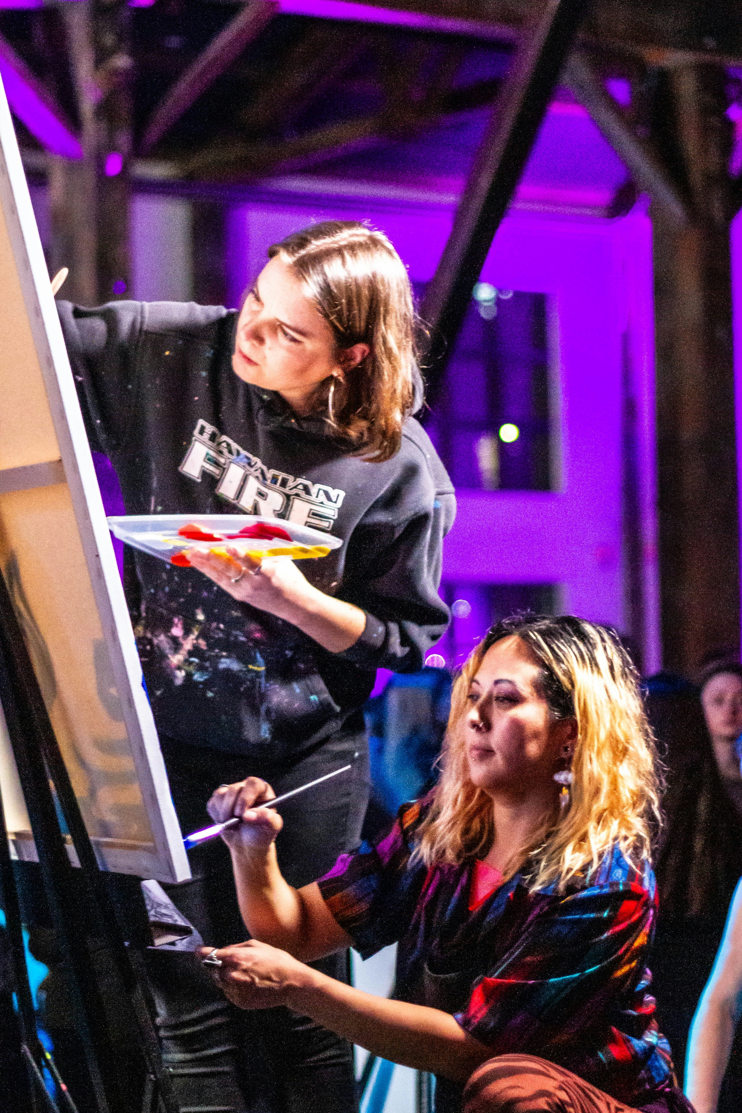 Women painting with brushes and palettes at an art class