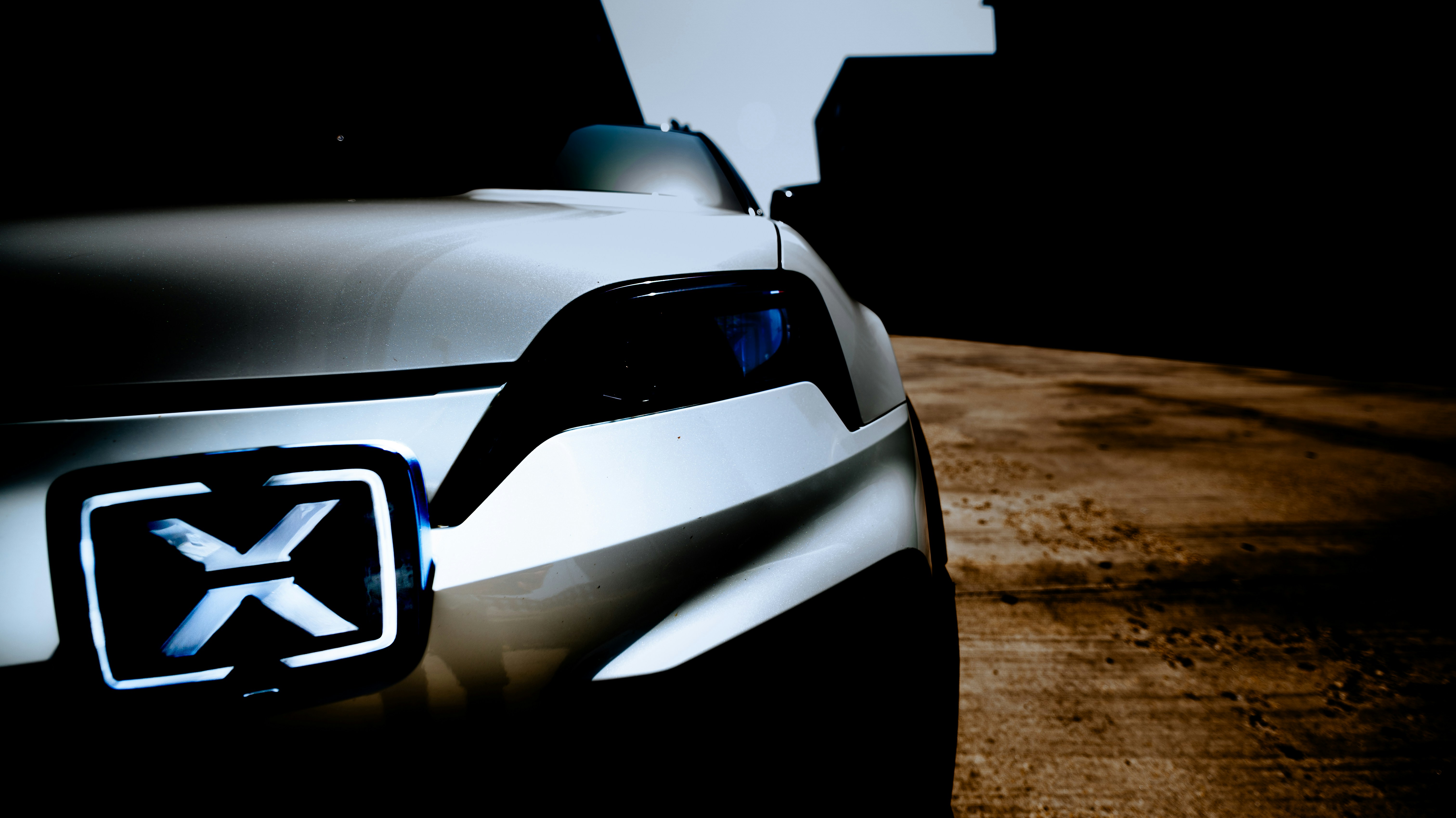 Davanti di un'auto futuristica con un logo a x illuminato.