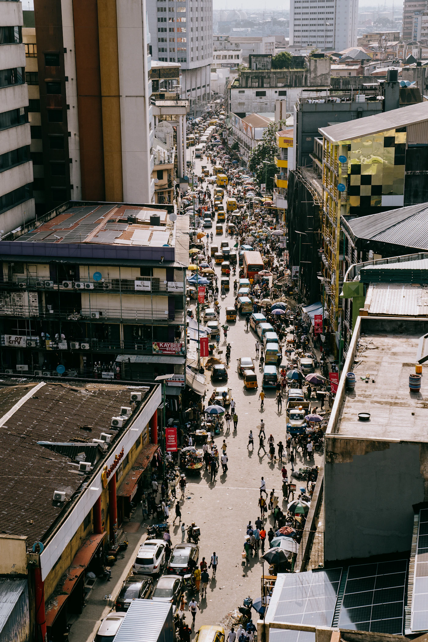 Busy Lagos-style city street with dense traffic and pedestrians seen from above
