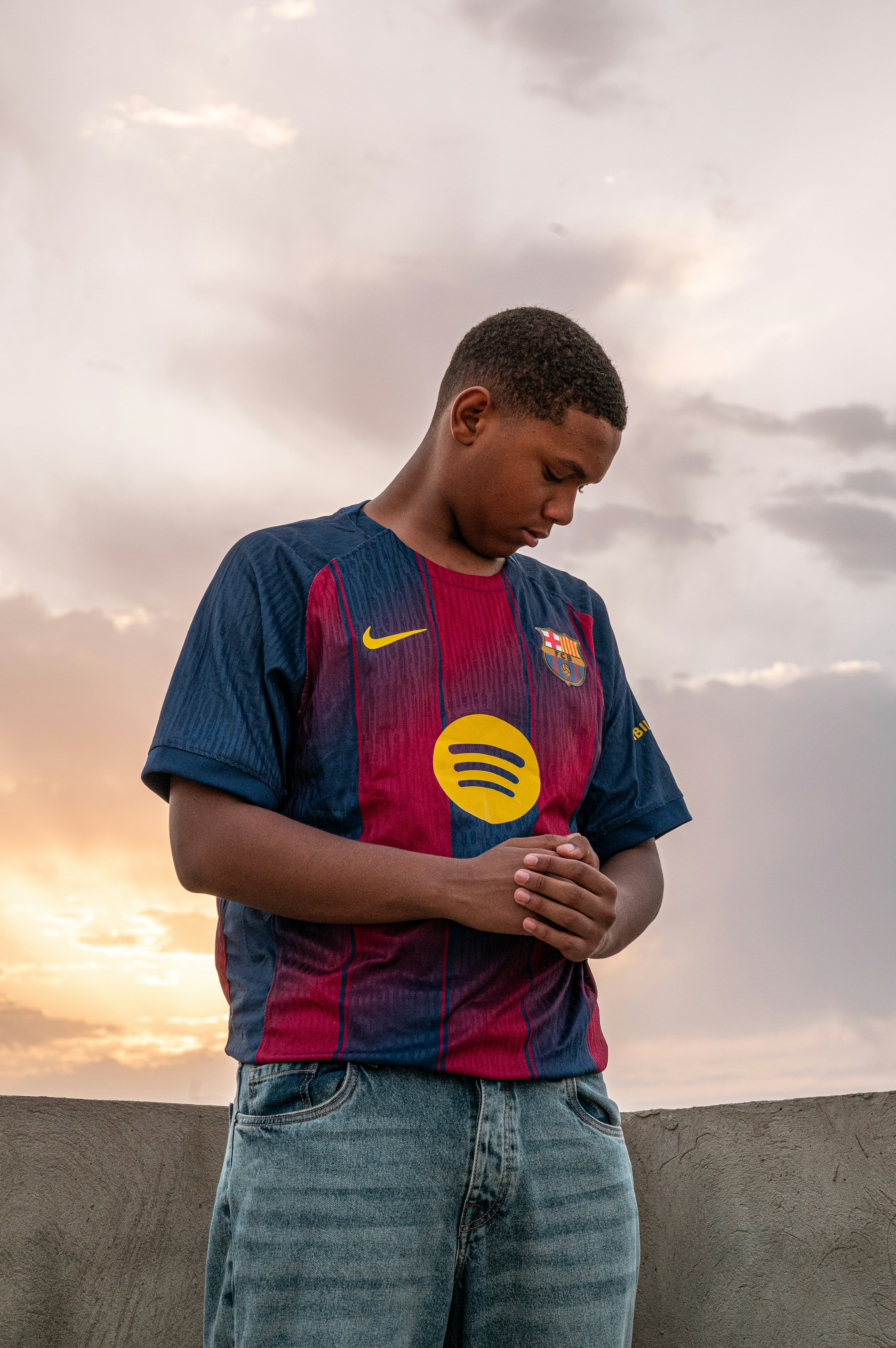Pria dengan jersey Barcelona menatap ke bawah saat matahari terbenam.