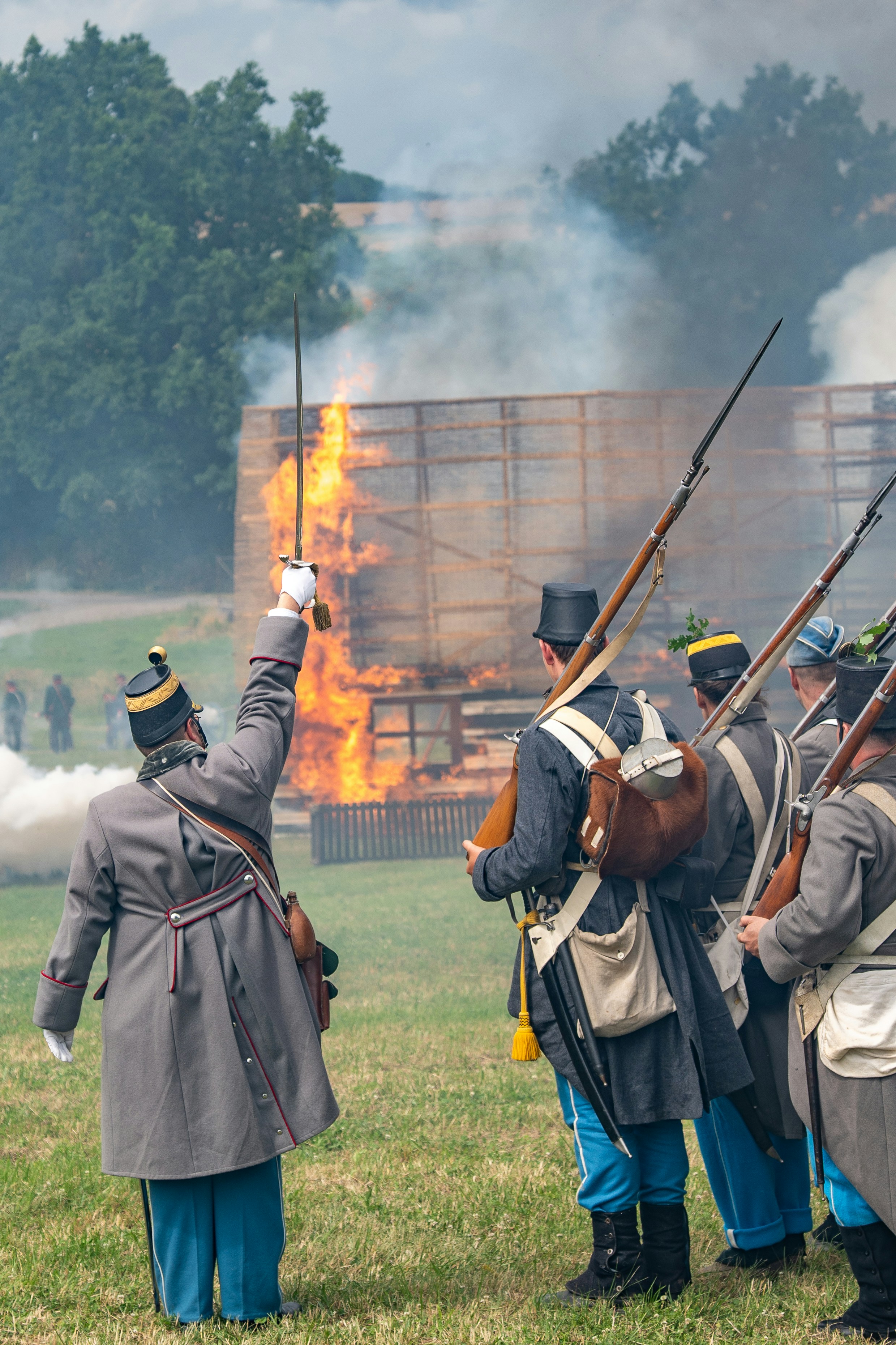Reencenação da guerra civil com soldados e um prédio em chamas.