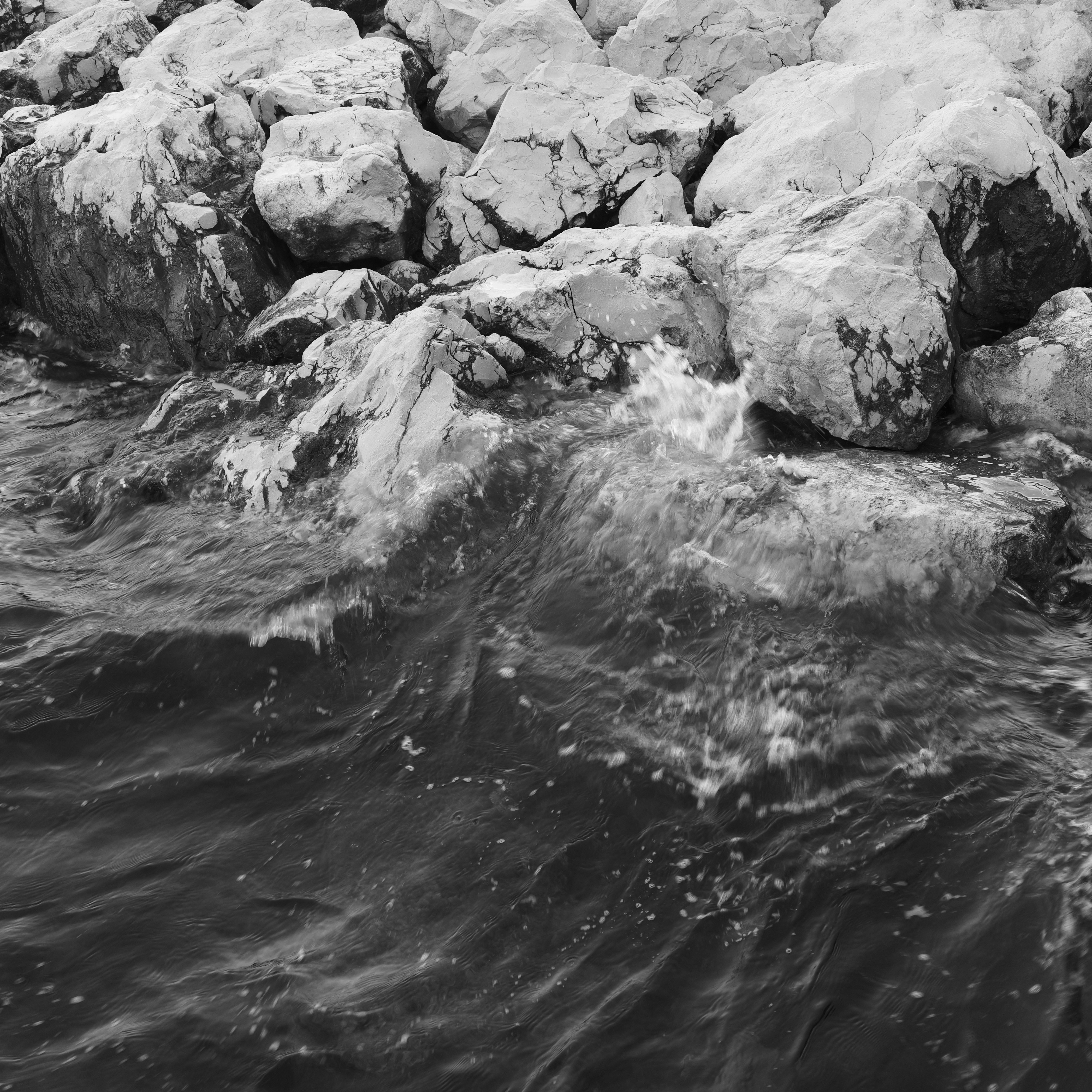 Waves breaking on rocky shore in monochrome