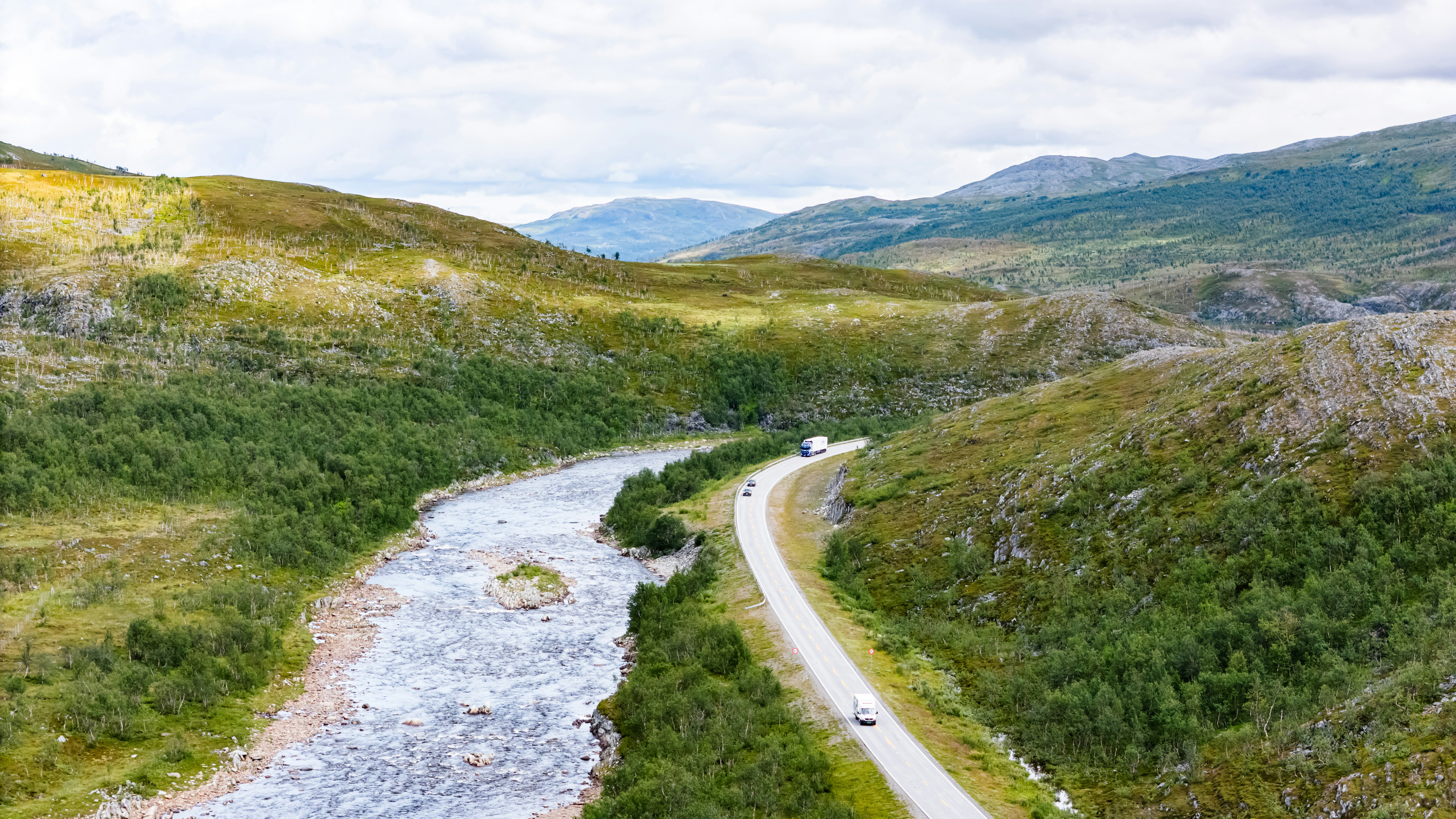 Winding river and road in a green mountainous landscape.