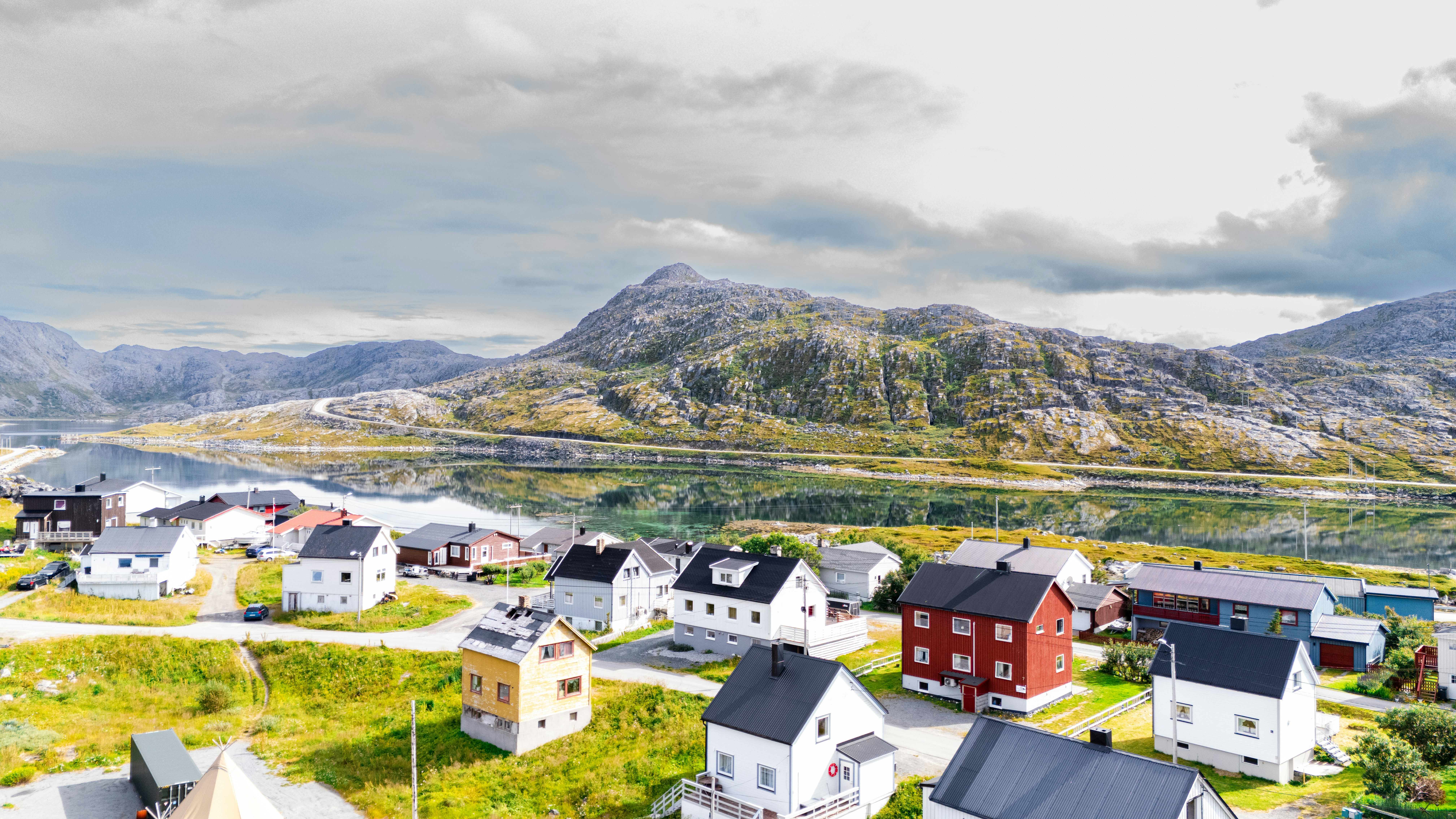 Colorful houses in a village by a lake with mountains.