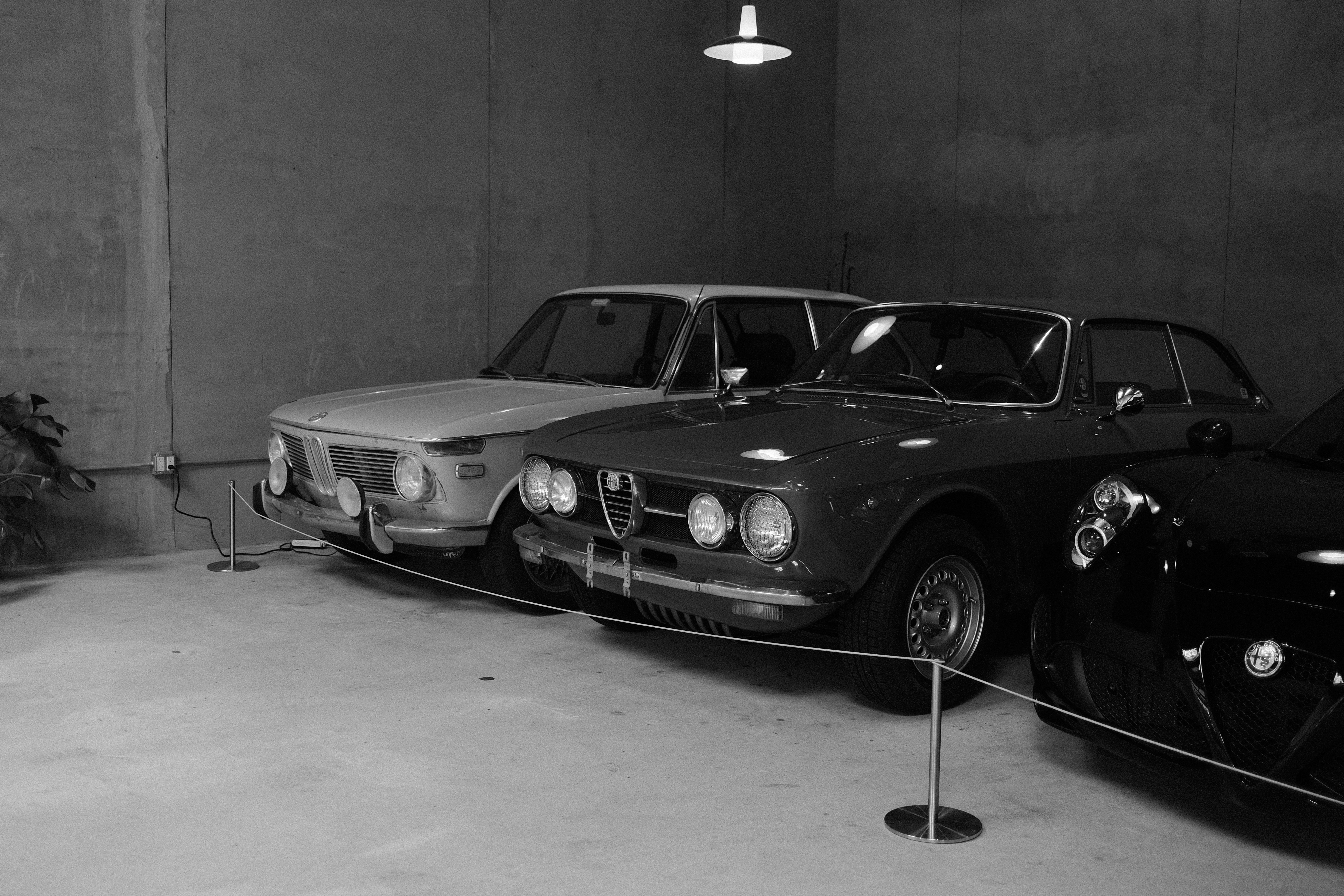 Le auto d'epoca esposte in un ambiente monocromatico e interno.