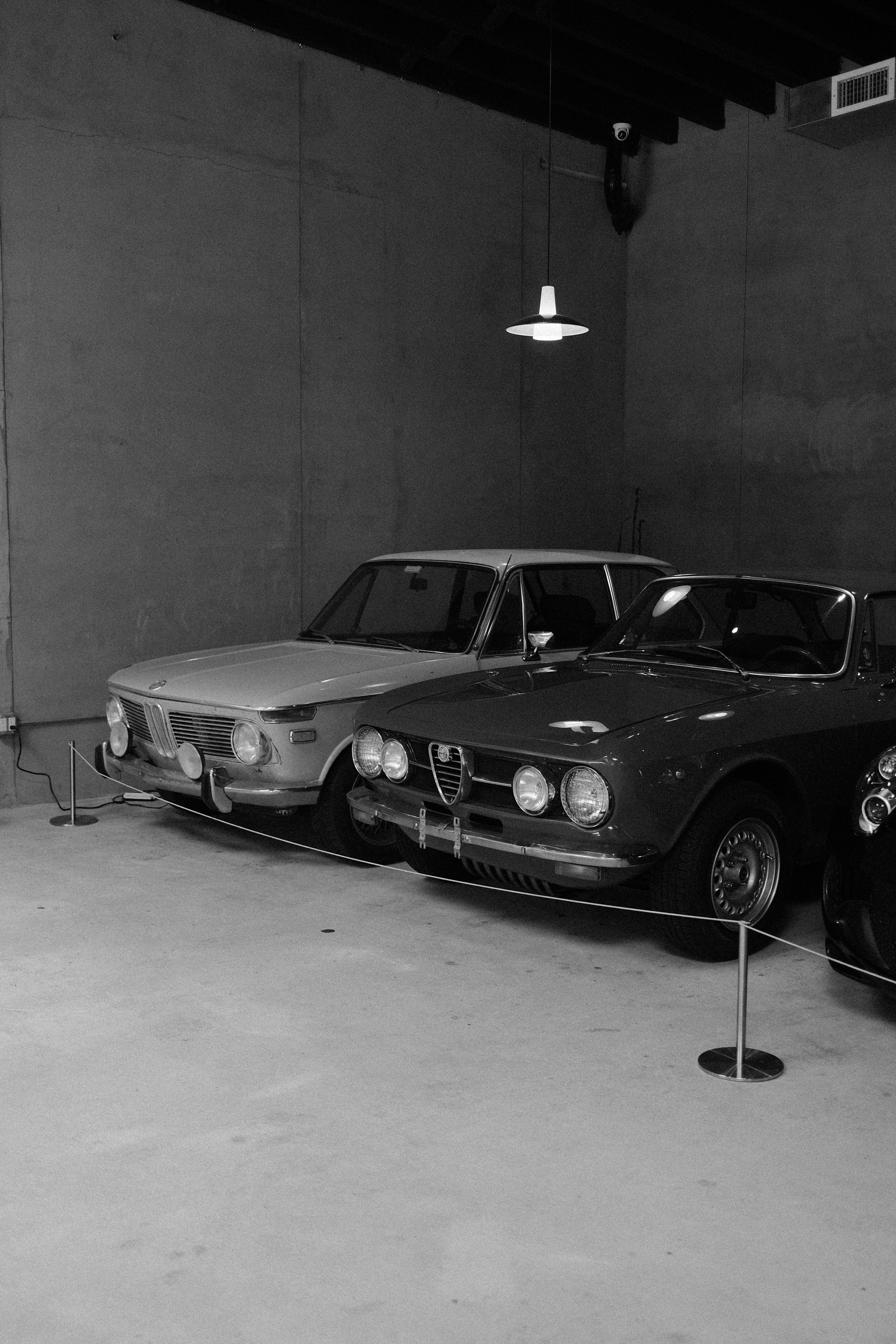 Due auto d'epoca parcheggiate in un garage poco illuminato.