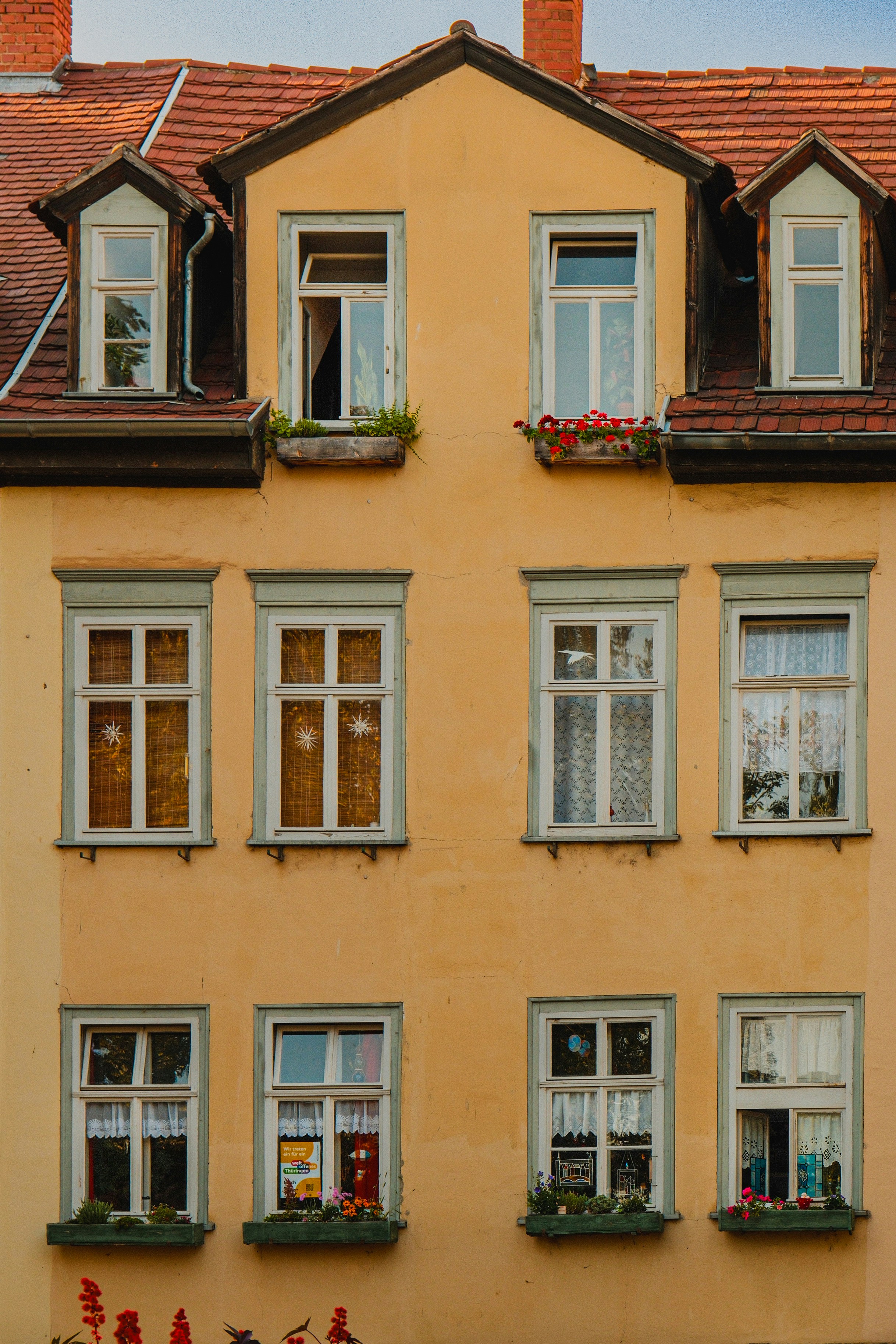 Yellow building facade with red roof and multiple windows.