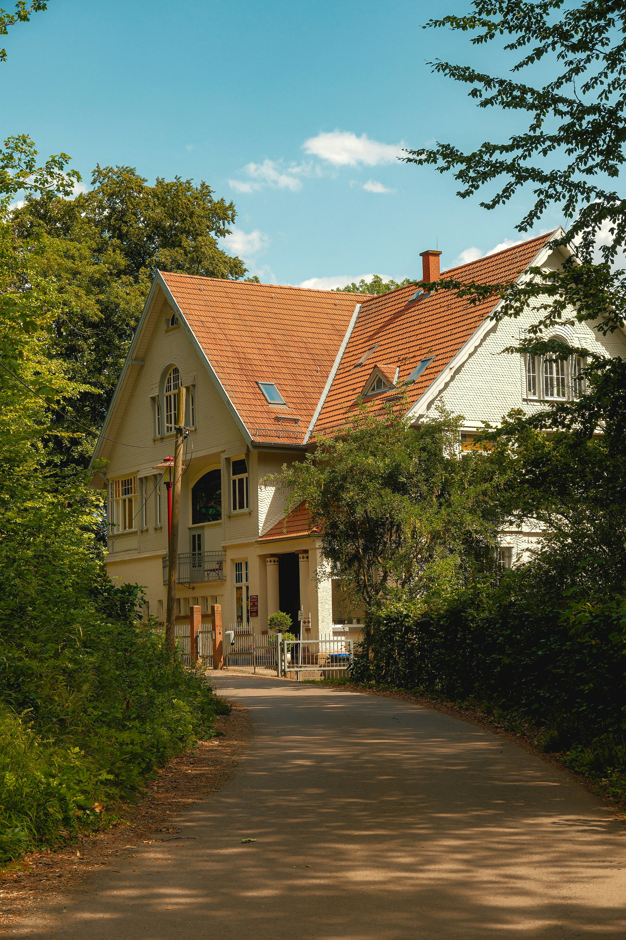 A house with a red roof visible through green foliage.