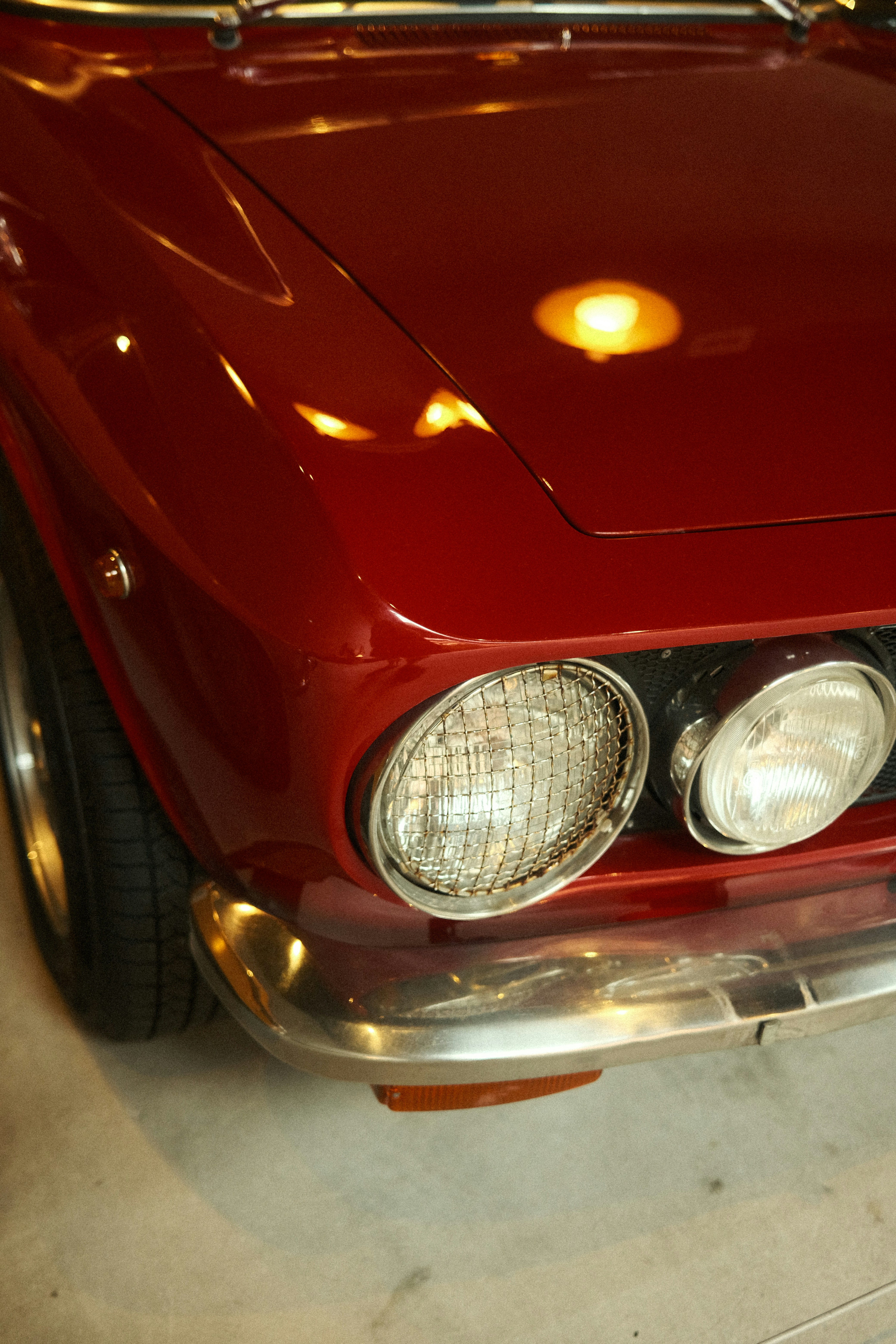 Anteriore d'auto rossa vintage con fari e paraurti cromato.