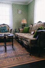 A vintage living room with ornate furniture and green wallpaper